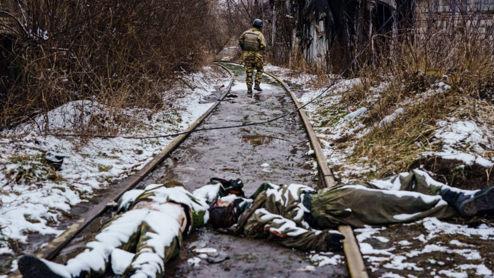 A Ukrainian soldier wanders down the railway to inspect something, past the bodies of dead Russian soldiers where fighting took place with Russian forces on the outskirts of Irpin, Ukraine, Tuesday, March 1, 2022.