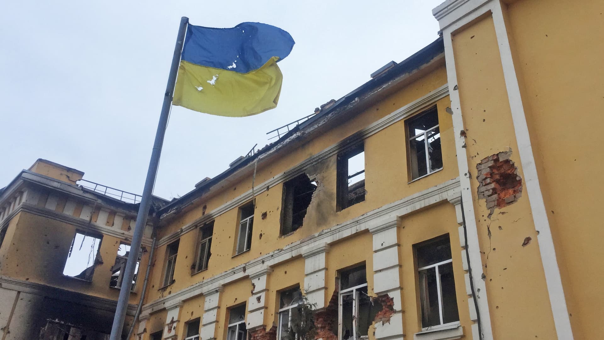 The Ukrainian national flag is seen in front of a school which, according to local residents, was on fire after shelling, as Russia's invasion of Ukraine continues, in Kharkiv, Ukraine February 28, 2022.