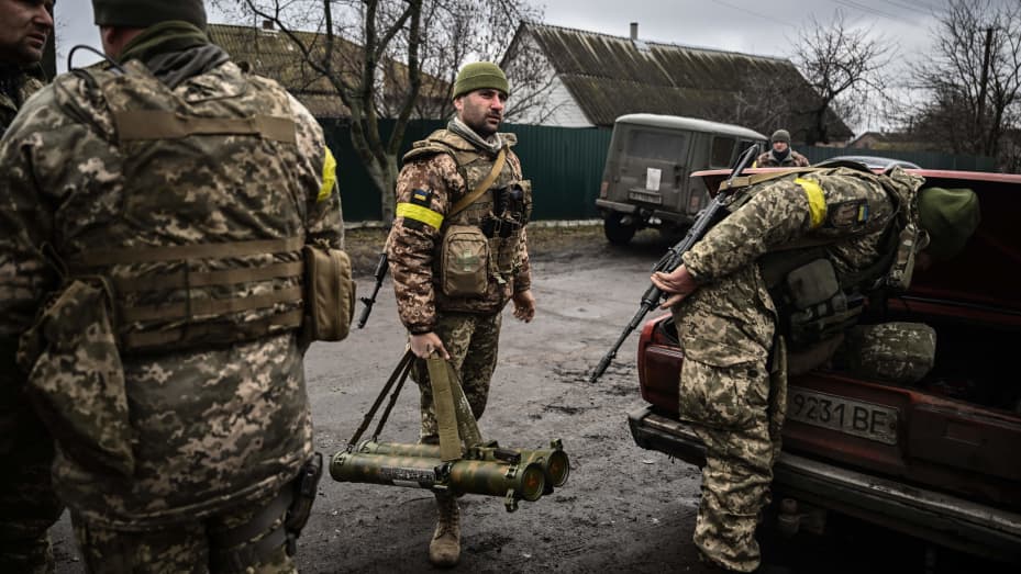 Ukrainian soldiers unload weapons from the trunk of an old car, northeast of Kyiv on March 3, 2022.