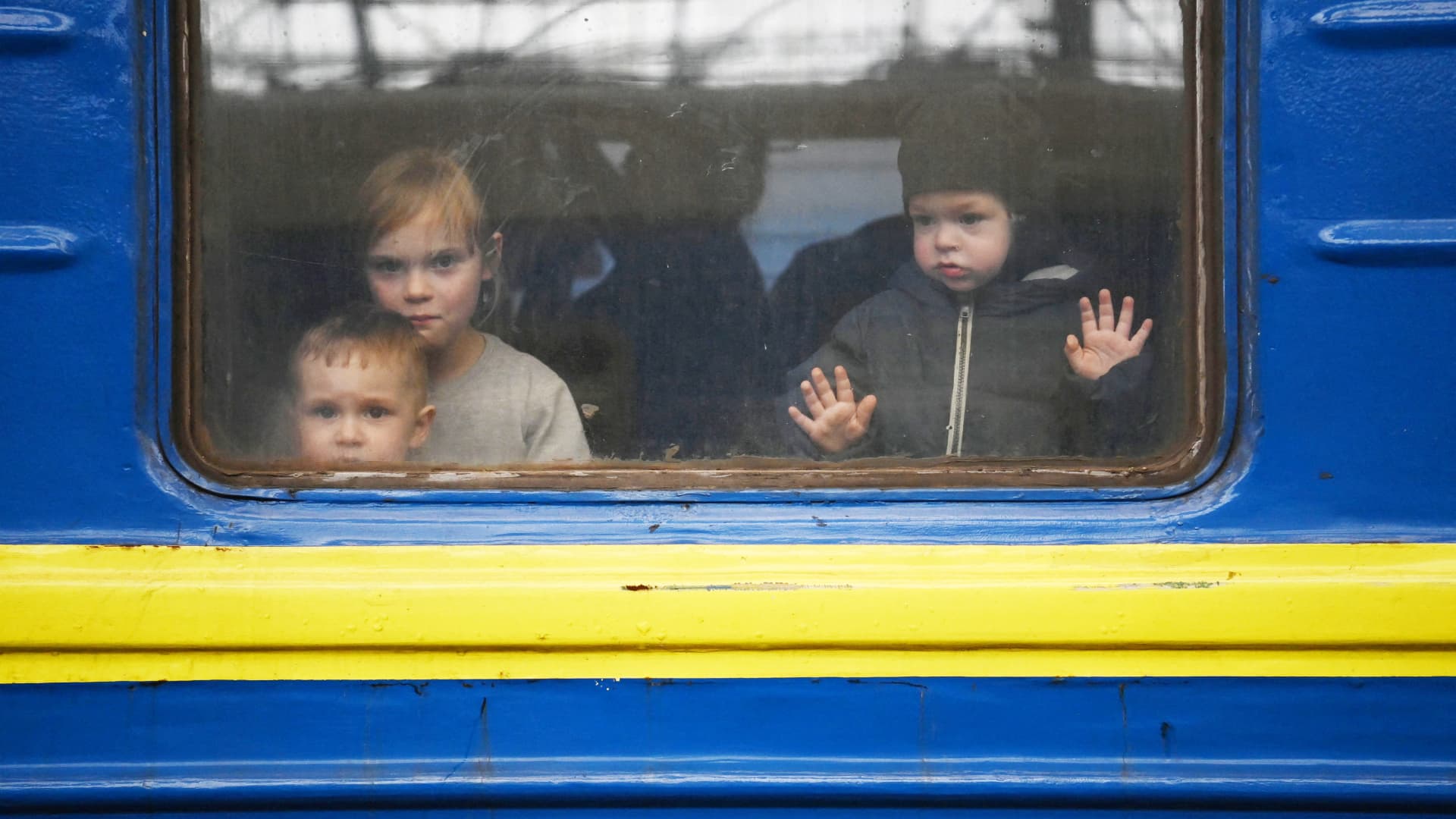 Children look out from a carriage window as a train prepares to depart from a station in Lviv, western Ukraine, enroute to the town of Uzhhorod near the border with Slovakia, on March 3, 2022.