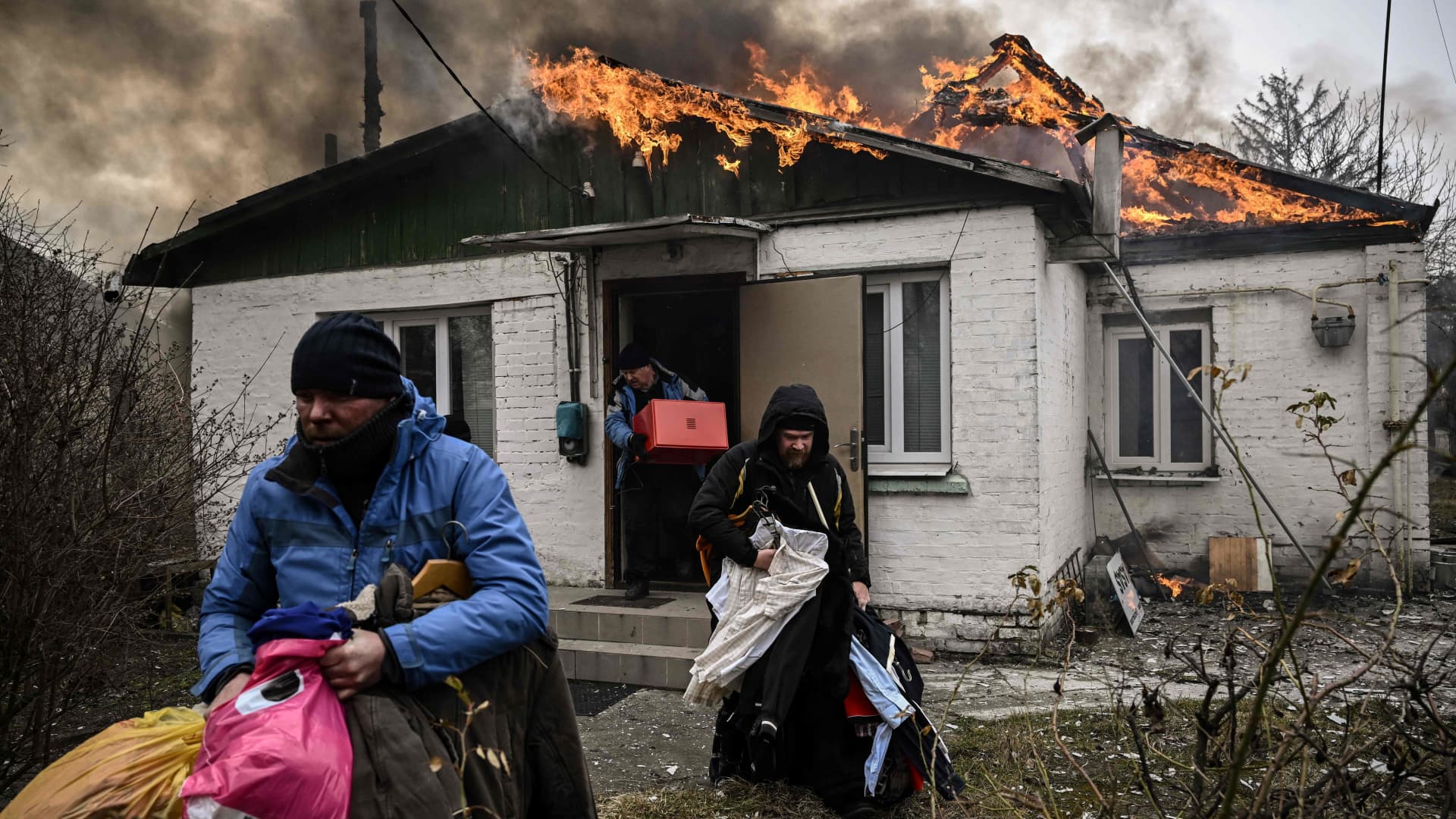 People remove personal belongings from a burning house after being shelled in the city of Irpin, outside Kyiv, Ukraine, on March 4, 2022.