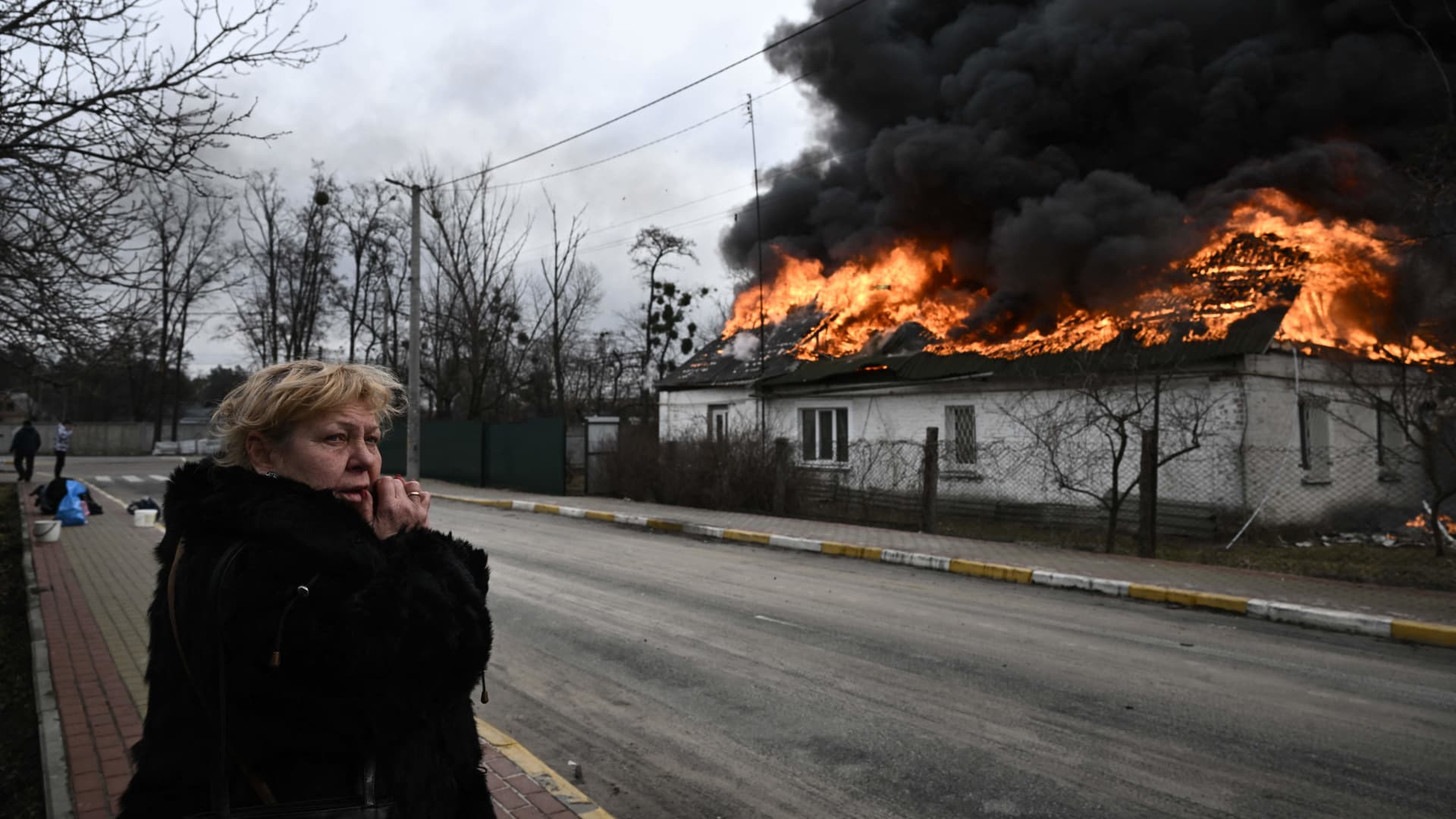 A woman reacts as she stands in front of a house burning after being shelled in the city of Irpin, outside Kyiv, on March 4, 2022.