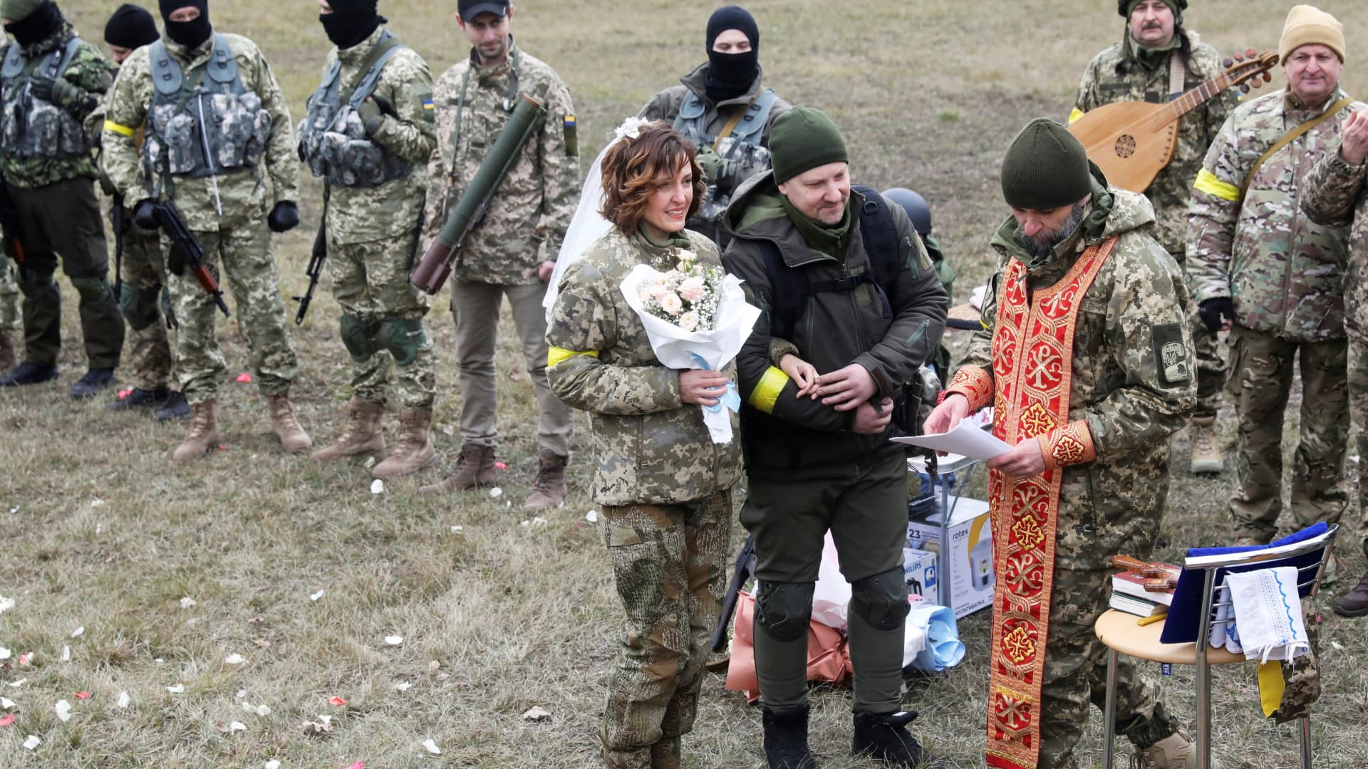 Members of the Ukrainian Territorial Defence Forces Lesia Ivashchenko and Valerii Fylymonov listen to a priest at their wedding during Ukraine-Russia conflict, at a checkpoint in Kyiv, Ukraine March 6, 2022. 