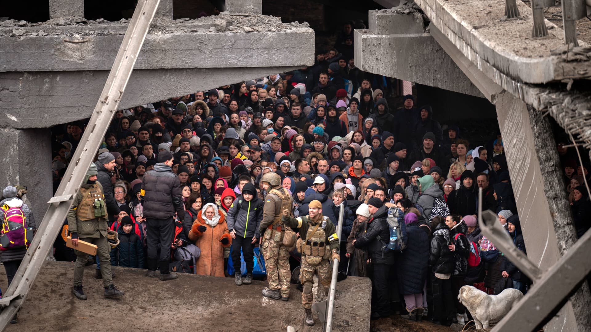 People cross on an improvised path under a bridge that was destroyed by a Russian airstrike, while fleeing the town of Irpin, Ukraine, Saturday, March 5, 2022.