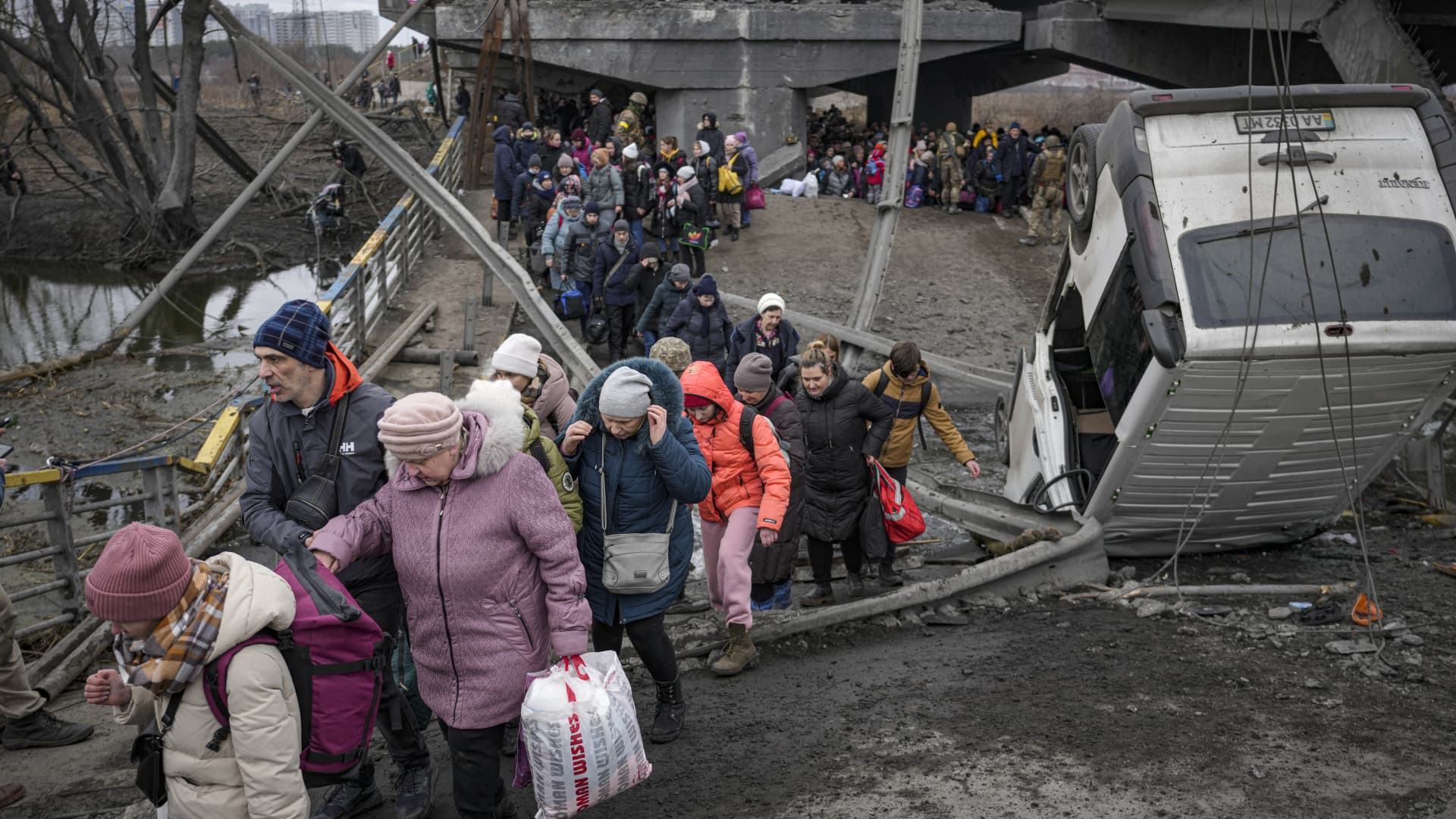 People cross on an improvised path under a bridge that was destroyed by a Russian airstrike, while fleeing the town of Irpin, Ukraine, Saturday, March 5, 2022.