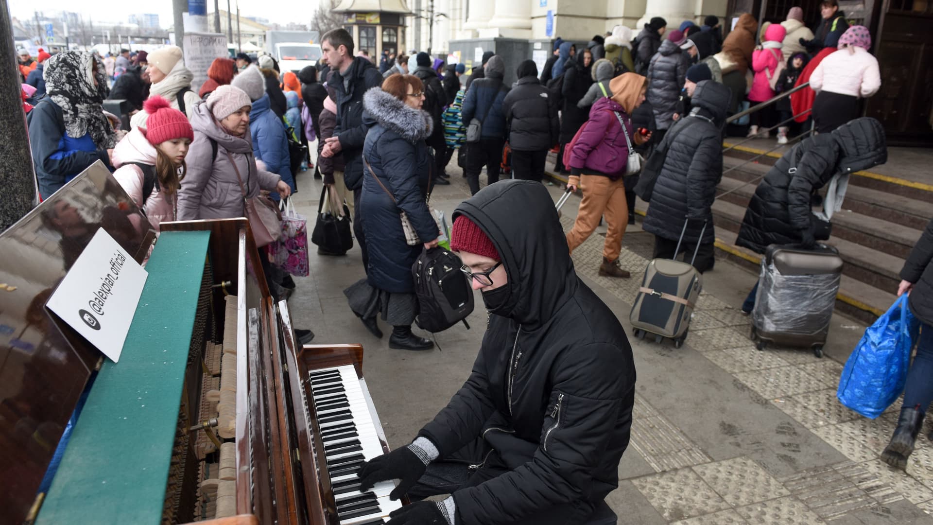 A man plays piano as people walk toward the railway station of the western Ukrainian city of Lviv on March 6, 2022, 11 days after Russia launched a military invasion on Ukraine.