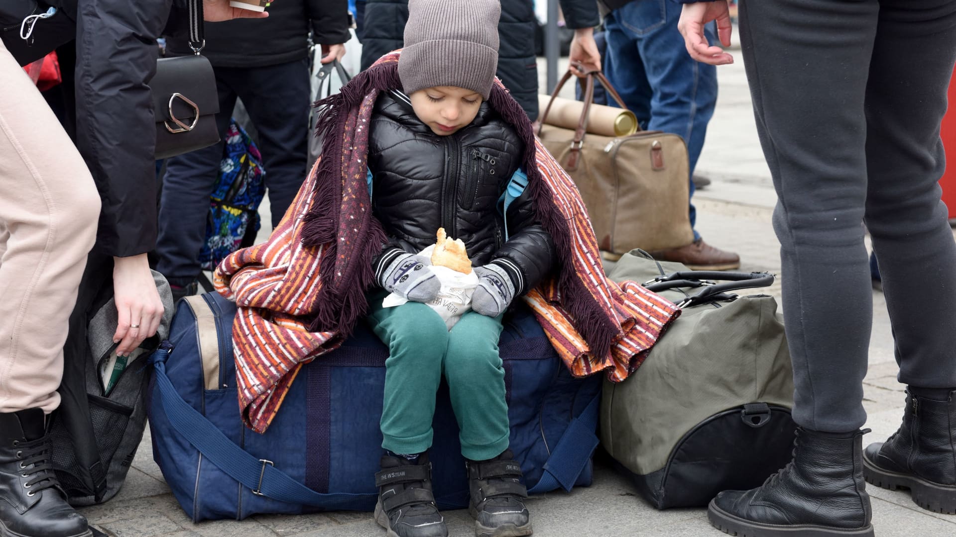 A child eats as people wait for a train to Poland at the railway station of the western Ukrainian city of Lviv on March 6, 2022, 11 days after Russia launched a military invasion on Ukraine.