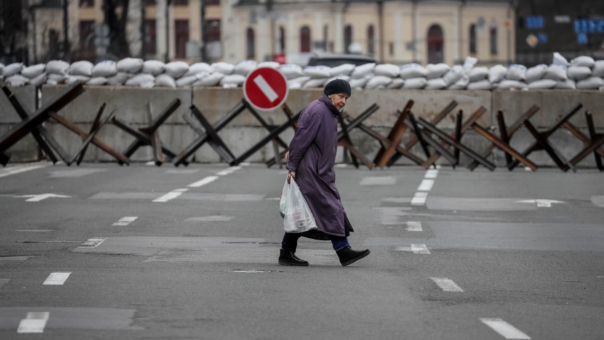 A woman crosses the street as anti-tank constructions are seen in central Kyiv, Ukraine March 7, 2022.
