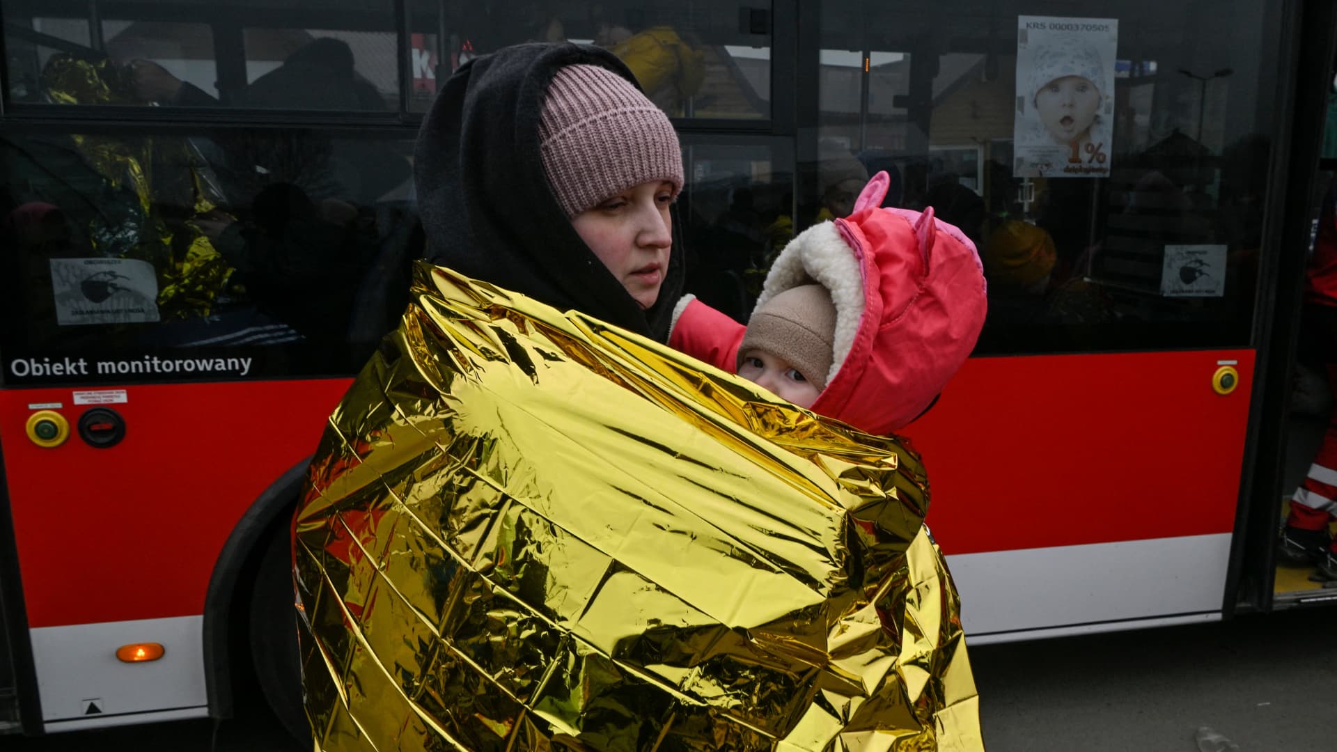 A woman with her child waits in freezing cold temperatures to get on bus, after crossing the Ukrainian border into Poland, at the Medyka border crossing in Poland, on March 7, 2022.