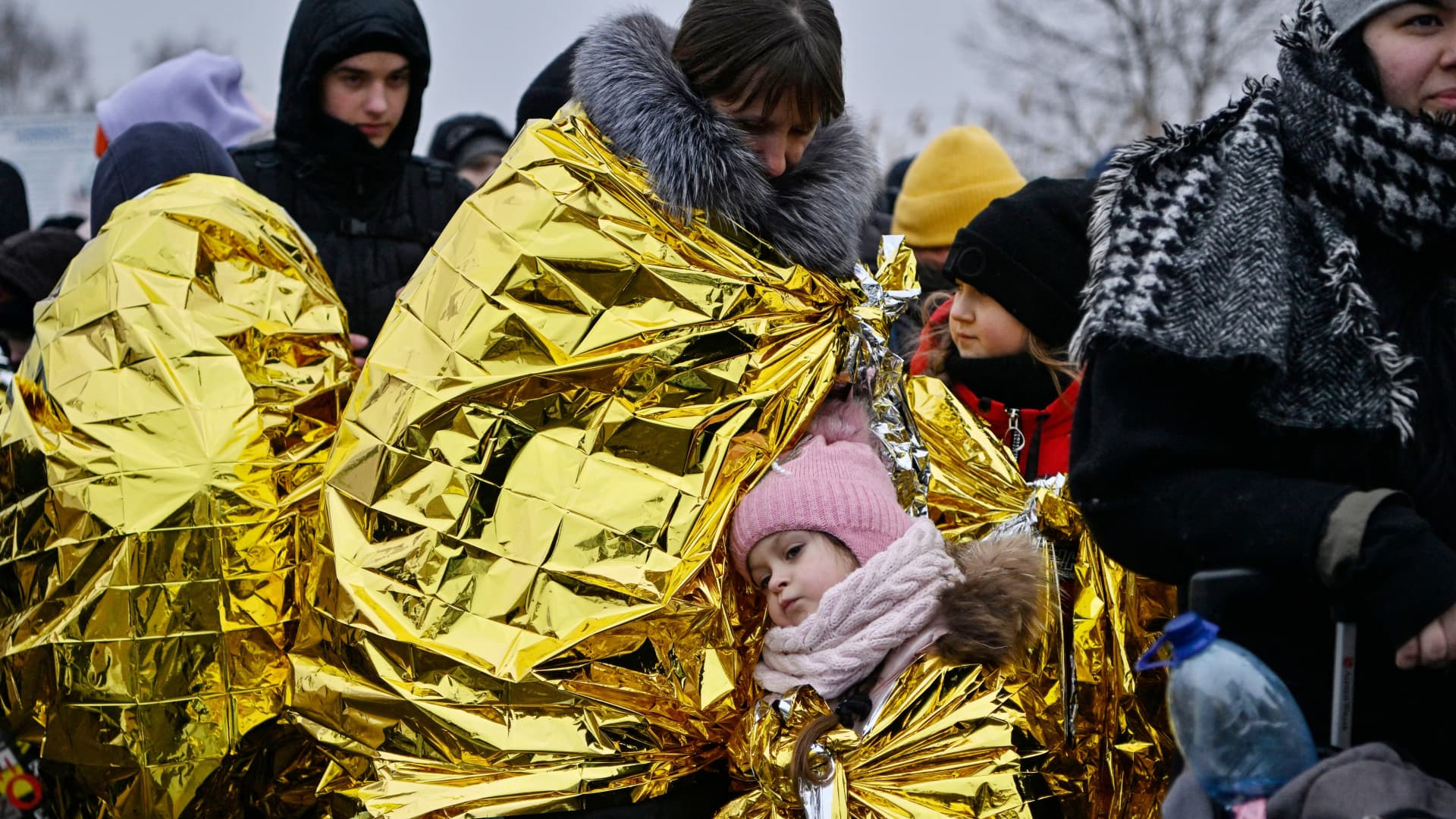 People wait in freezing cold temperatures to be transferred to a train station, after crossing the Ukrainian borders into Poland, at the Medyka border crossing in Poland, on March 7, 2022.
