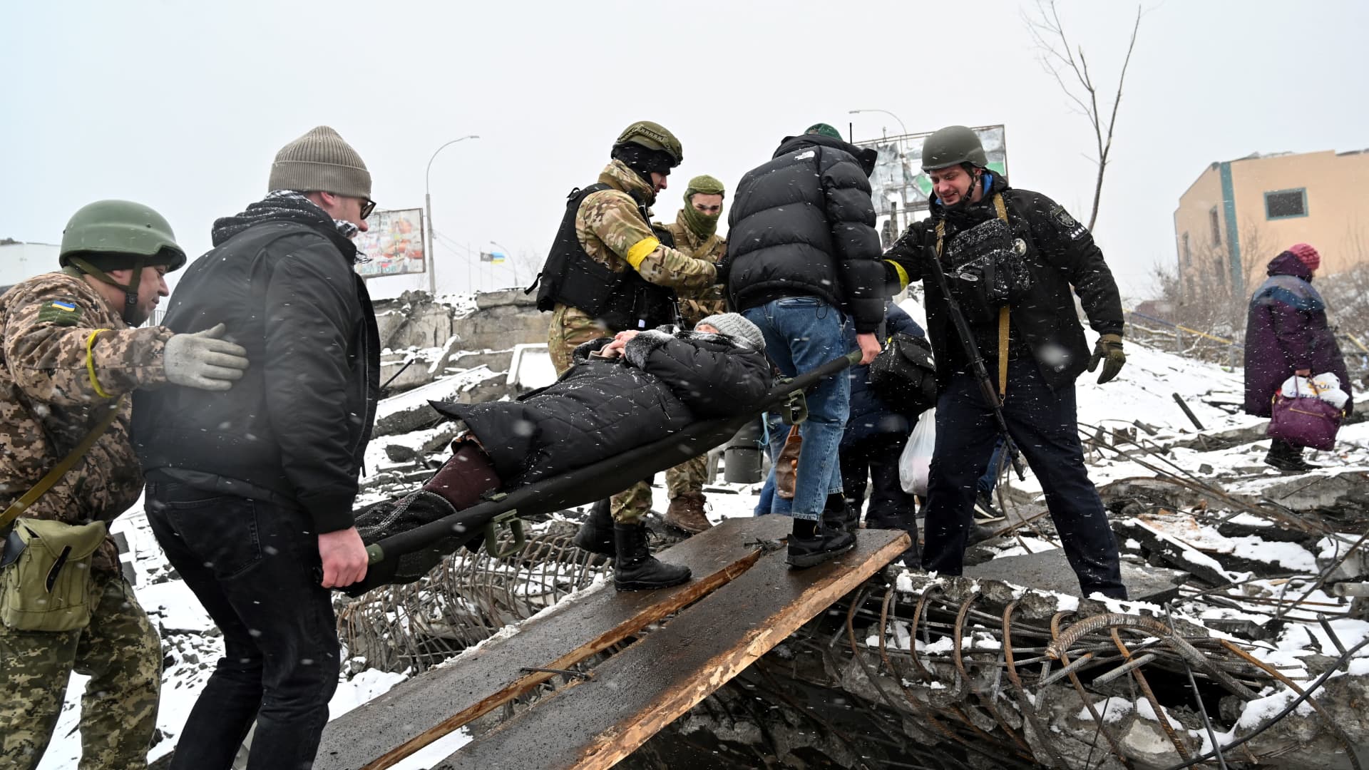 People carry a wounded woman during the evacuation by civilians of the city of Irpin, northwest of Kyiv, on March 8, 2022.