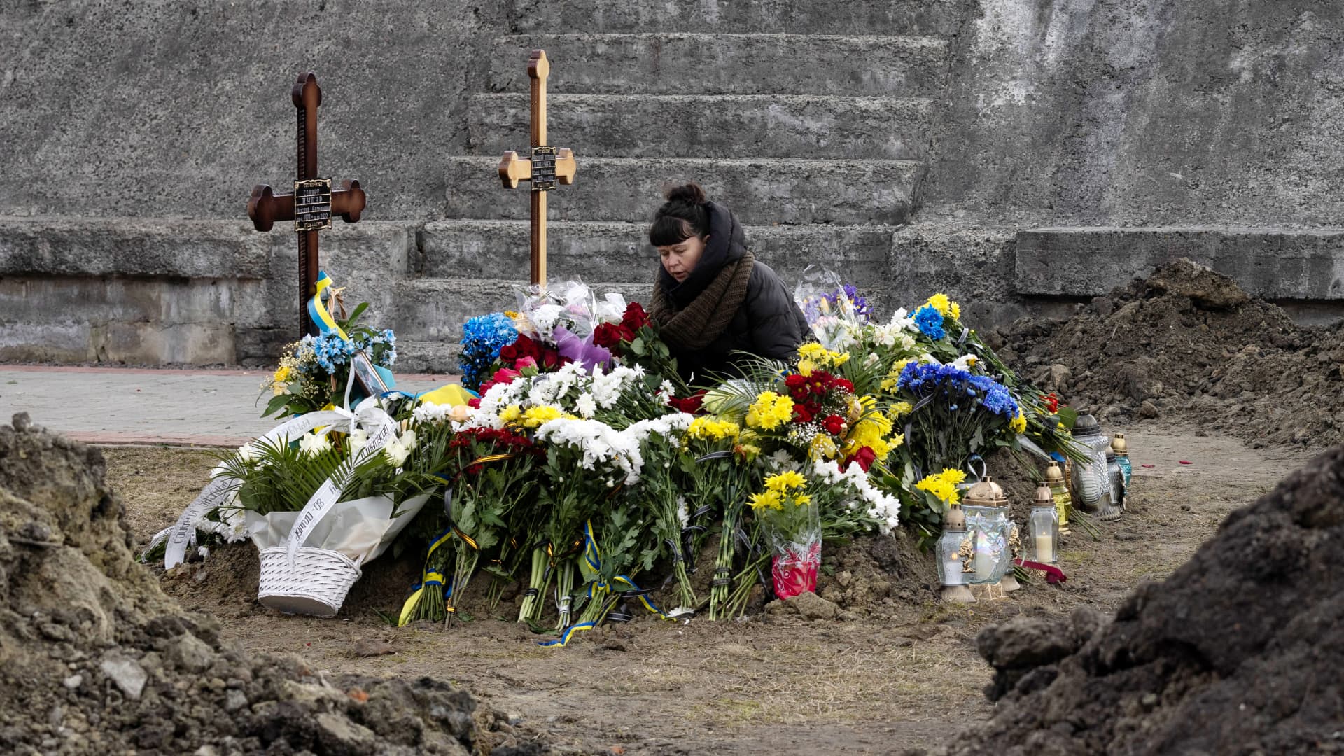 A woman stands besides two graves at Lychakiv cemetery after a joint funeral for two soldiers who died in the east of the country during recent fighting, on March 08, 2022 in Lviv, Ukraine.