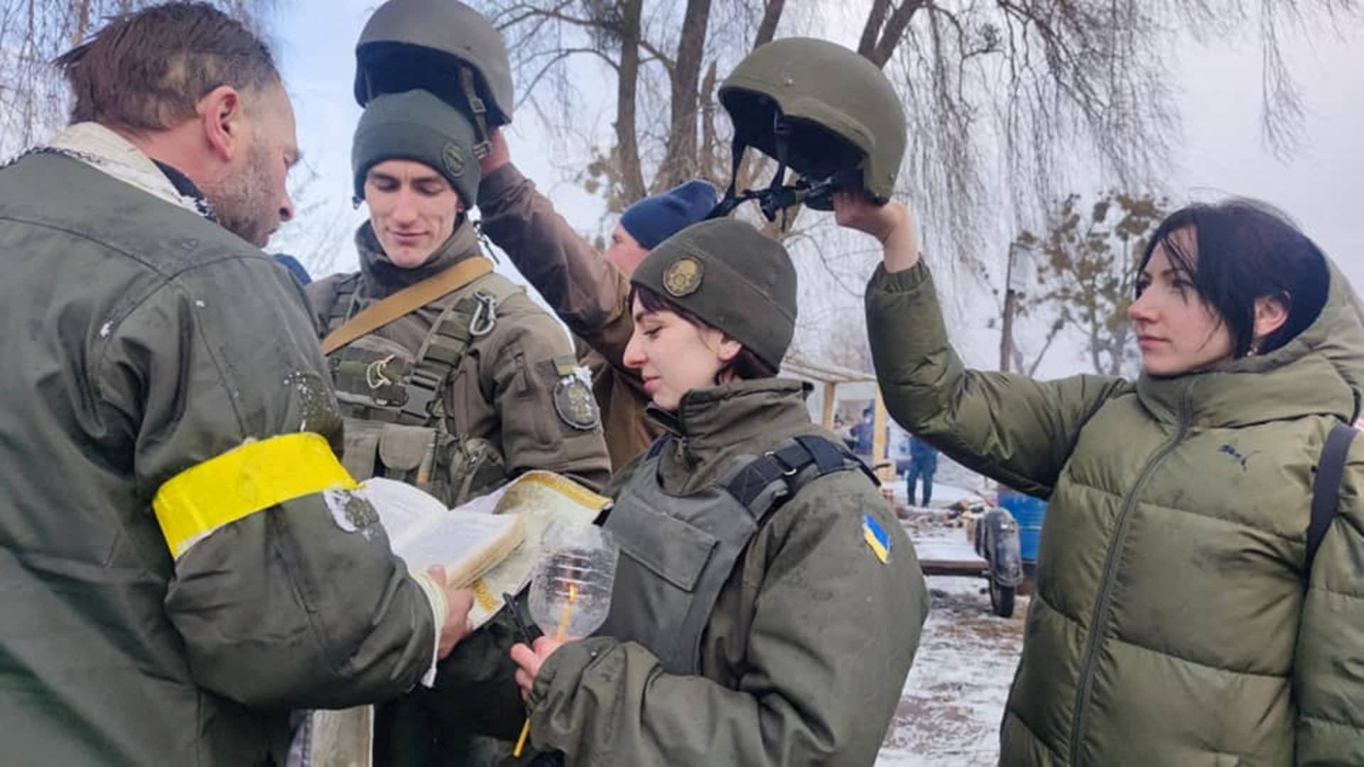 Members of the National Guard of Ukraine Oleksandr and Olena listen to a priest at their wedding during Ukraine-Russia conflict, at a checkpoint in unknown location, in Ukraine, in this handout picture released March 8, 2022.
