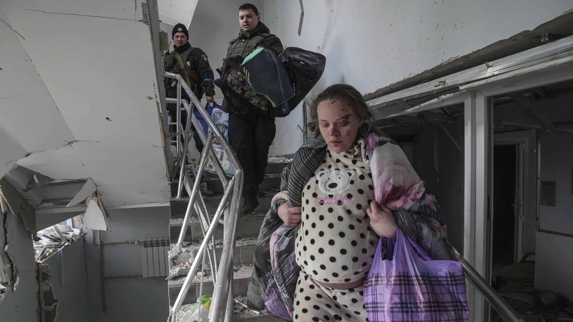 An injured pregnant woman walks downstairs in a maternity hospital damaged by shelling in Mariupol, Ukraine, Wednesday, March 9, 2022.