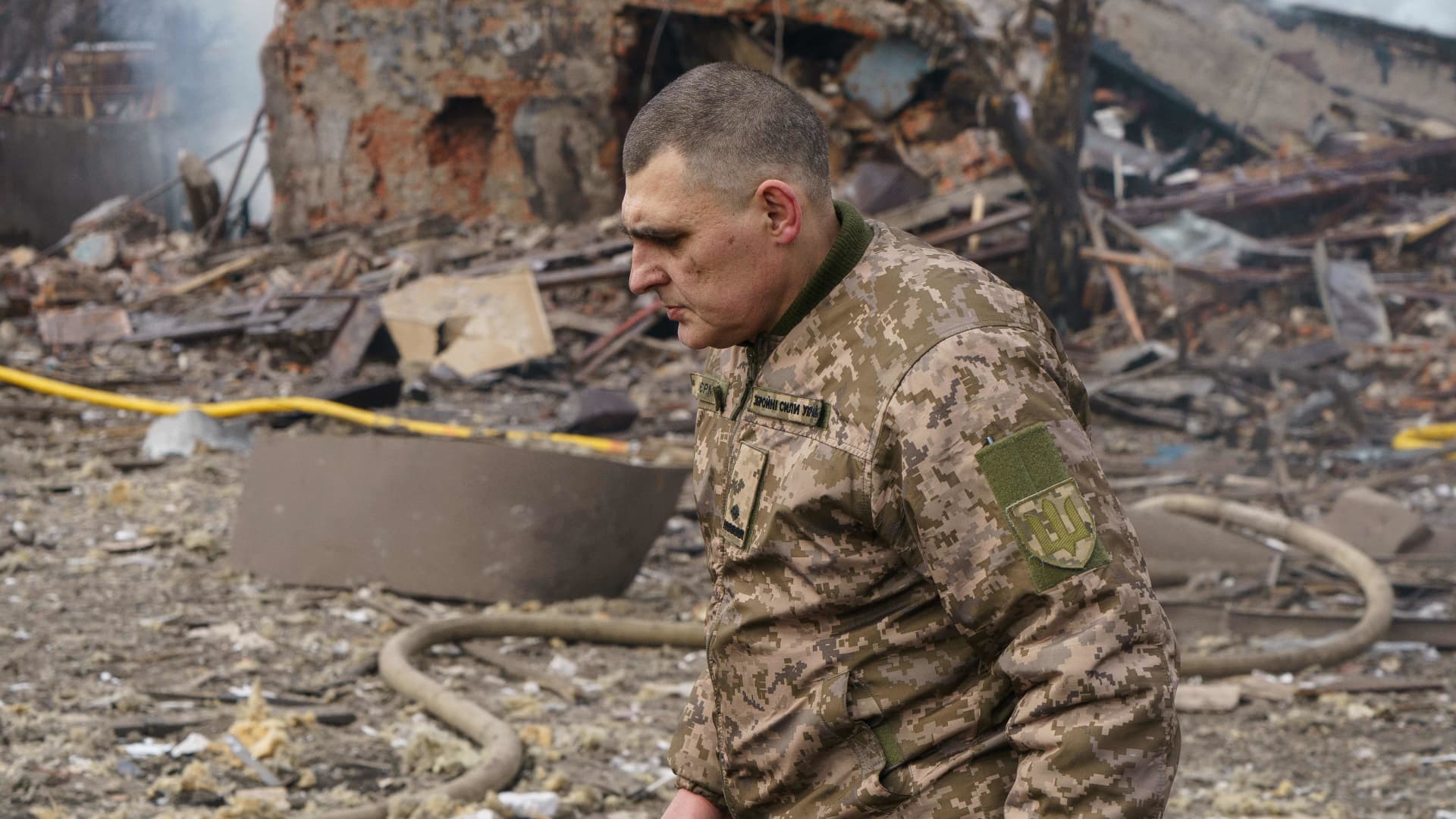 Ukraine army public affairs officer Valentin Yermolenko walks in front of a destroyed shoe factory following an airstrike in Dnipro on March 11, 2022.