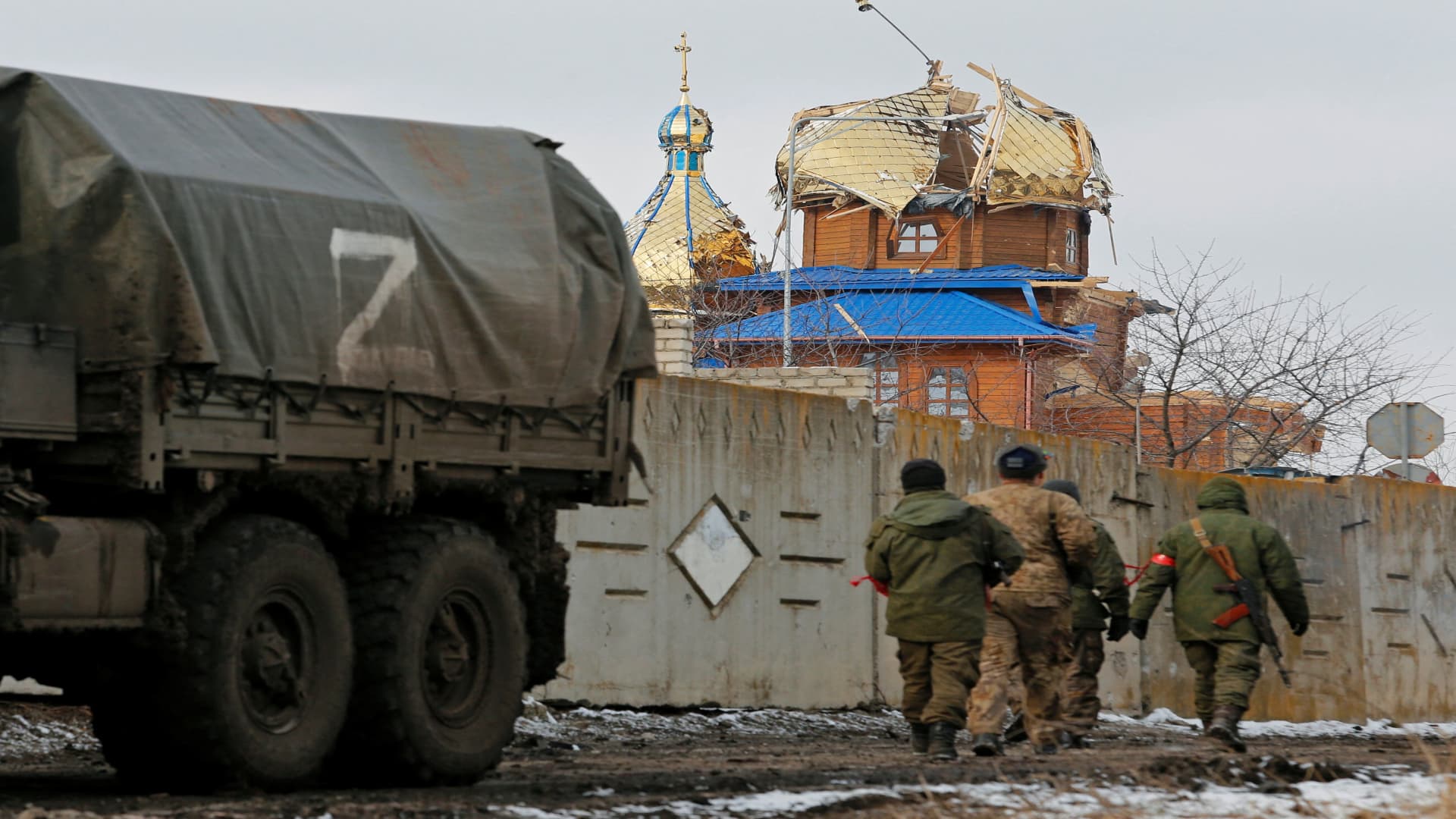 Service members of pro-Russian troops in uniforms without insignia walk near a church which was damaged during Ukraine-Russia conflict in the separatist-controlled town of Volnovakha in the Donetsk region, Ukraine March 11, 2022. 