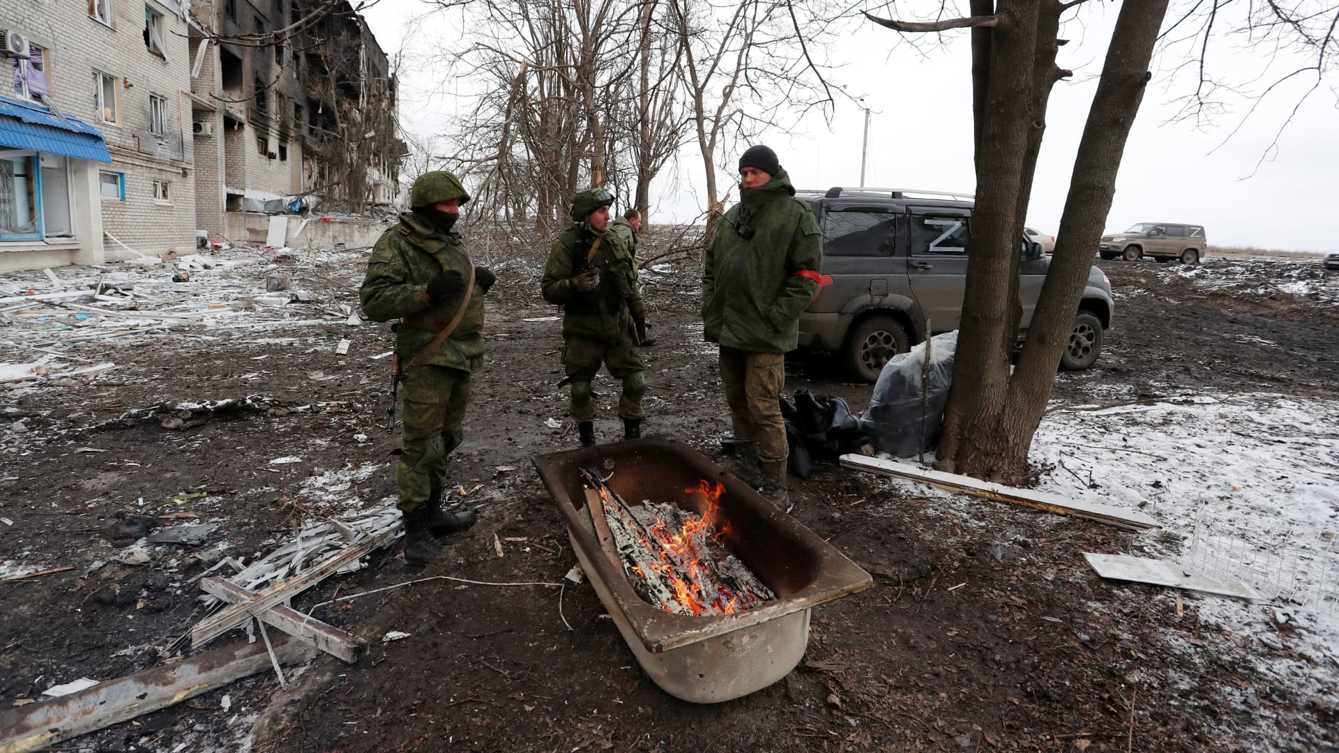 Service members of pro-Russian troops in uniforms without insignia gather around a fire outside a residential building which was damaged during Ukraine-Russia conflict in the separatist-controlled town of Volnovakha in the Donetsk region, Ukraine March 11, 2022. 