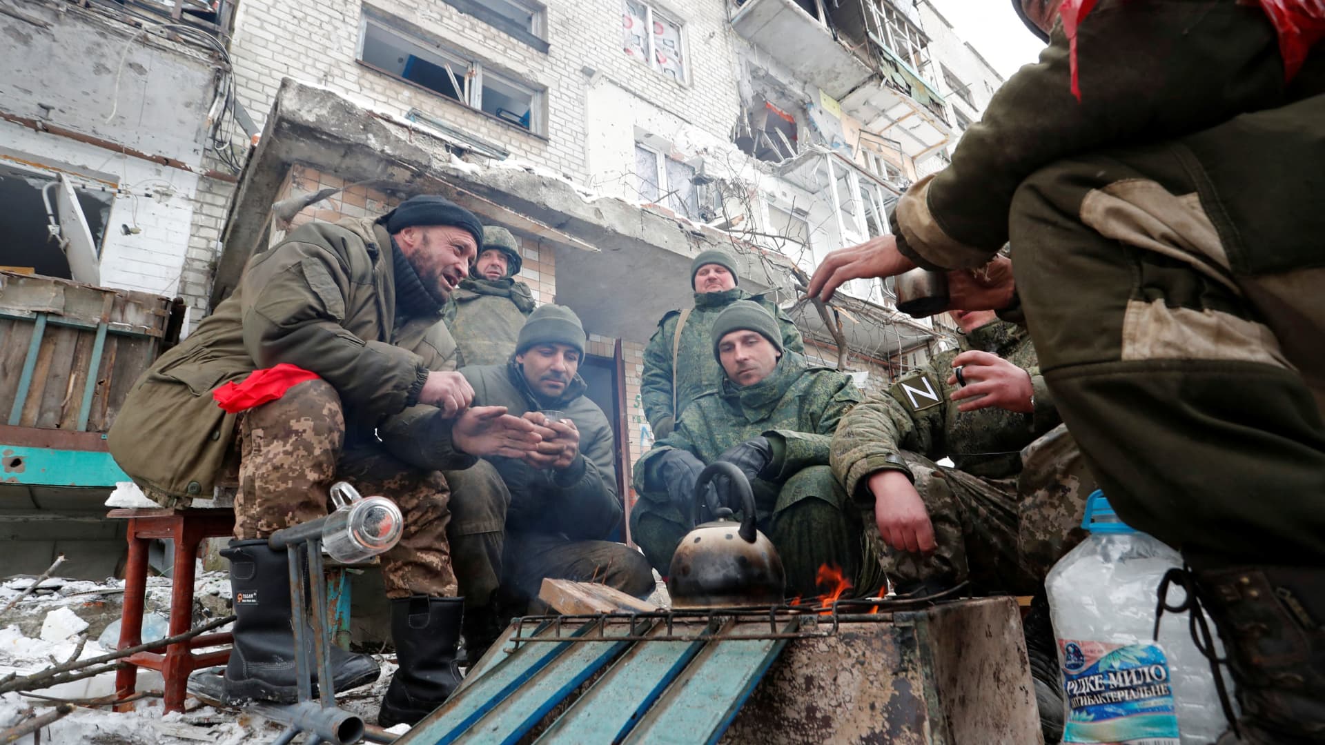 Service members of pro-Russian troops in uniforms without insignia gather around a fire outside a residential building which was damaged during Ukraine-Russia conflict in the separatist-controlled town of Volnovakha in the Donetsk region, Ukraine March 11, 2022.