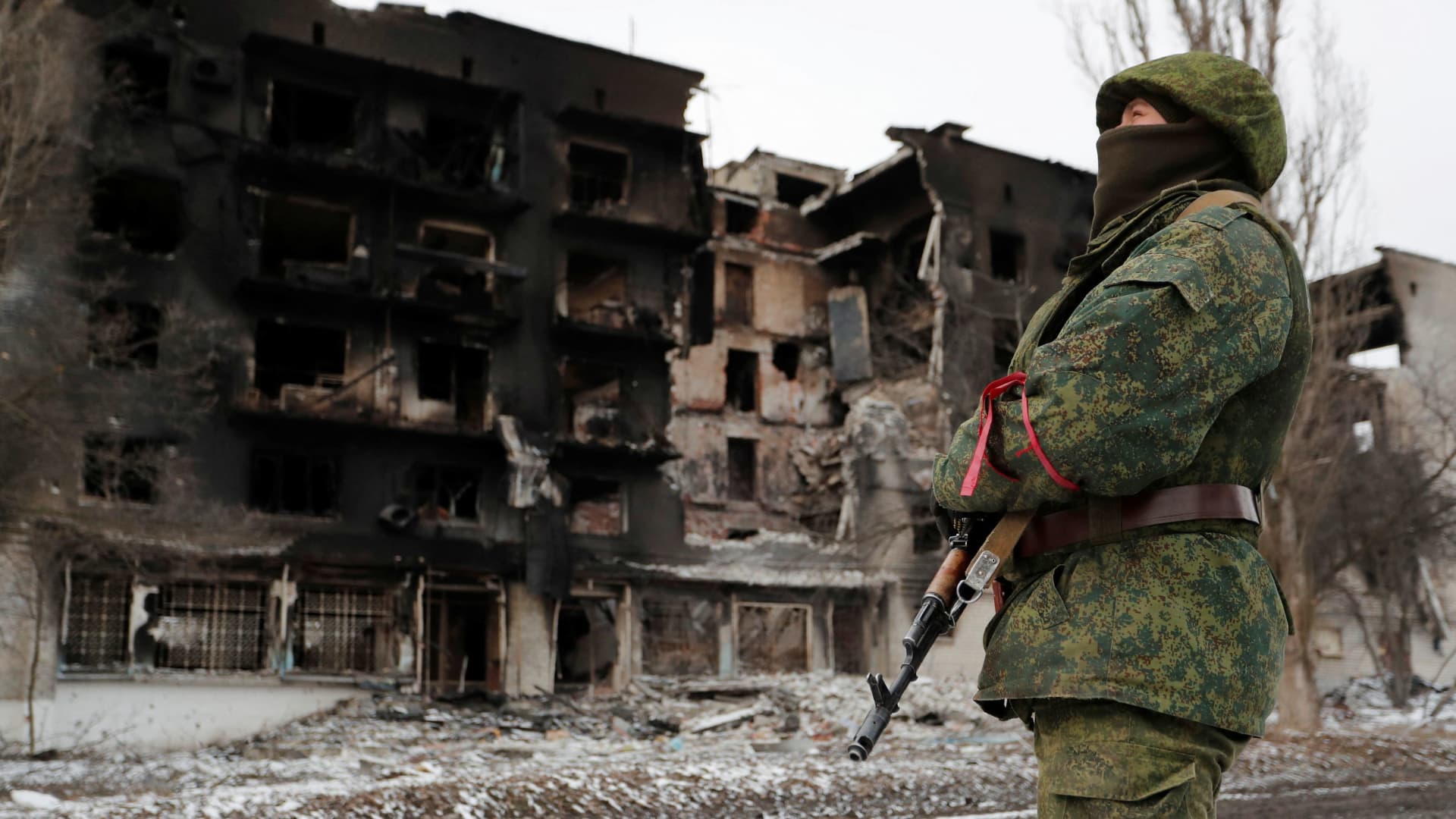 A service member of pro-Russian troops in uniform without insignia stands near a residential building which was heavily damaged during Ukraine-Russia conflict in the separatist-controlled town of Volnovakha in the Donetsk region, Ukraine March 11, 2022.