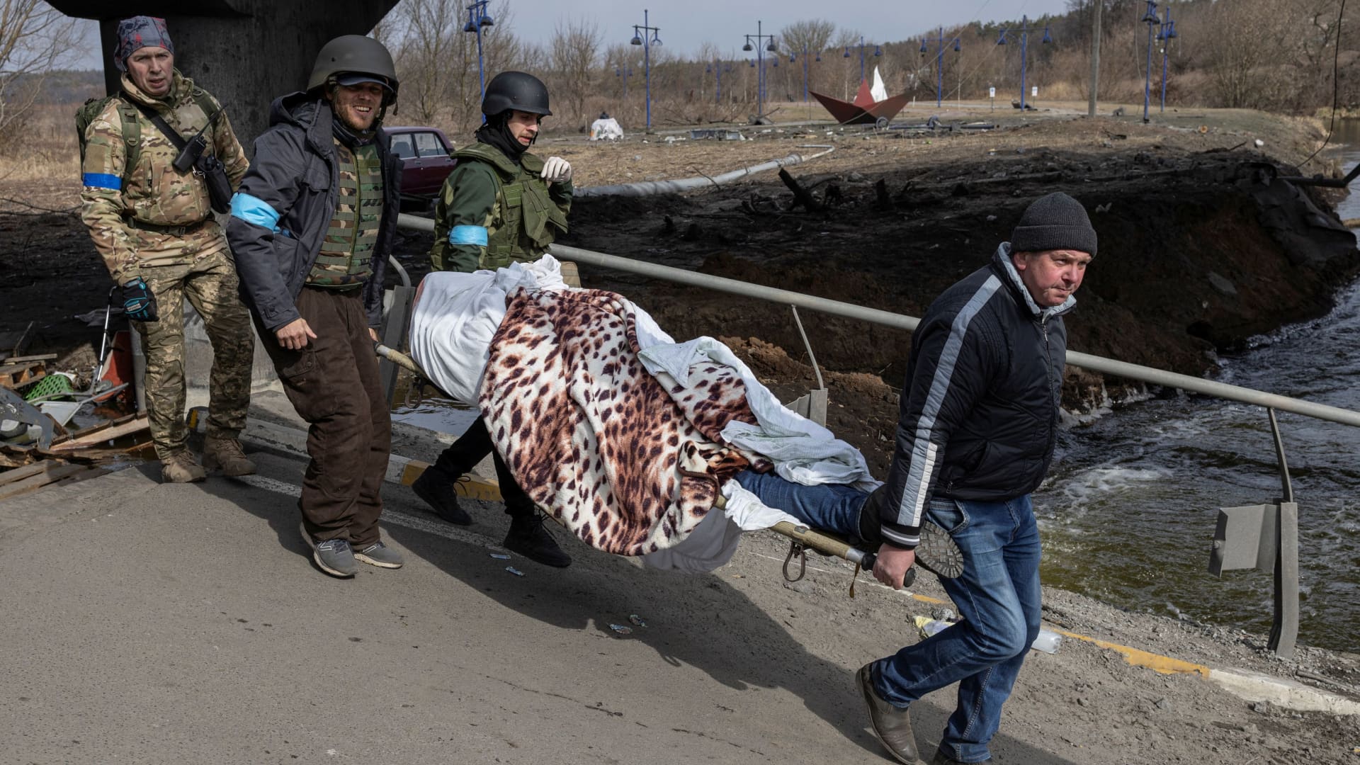 Ukrainian servicemen carry a dead body on stretcher as Russia's invasion of Ukraine continues, in the town of Irpin outside Kyiv, Ukraine, March 12, 2022.