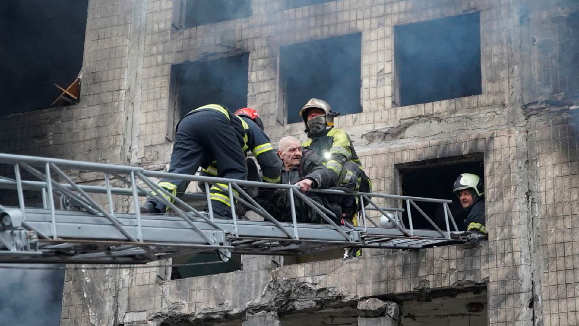Firefighters use a ladder to evacuate a man from a residential building that was struck, as Russia's attack on Ukraine continues, in Kyiv, Ukraine, in this handout picture released March 14, 2022. 