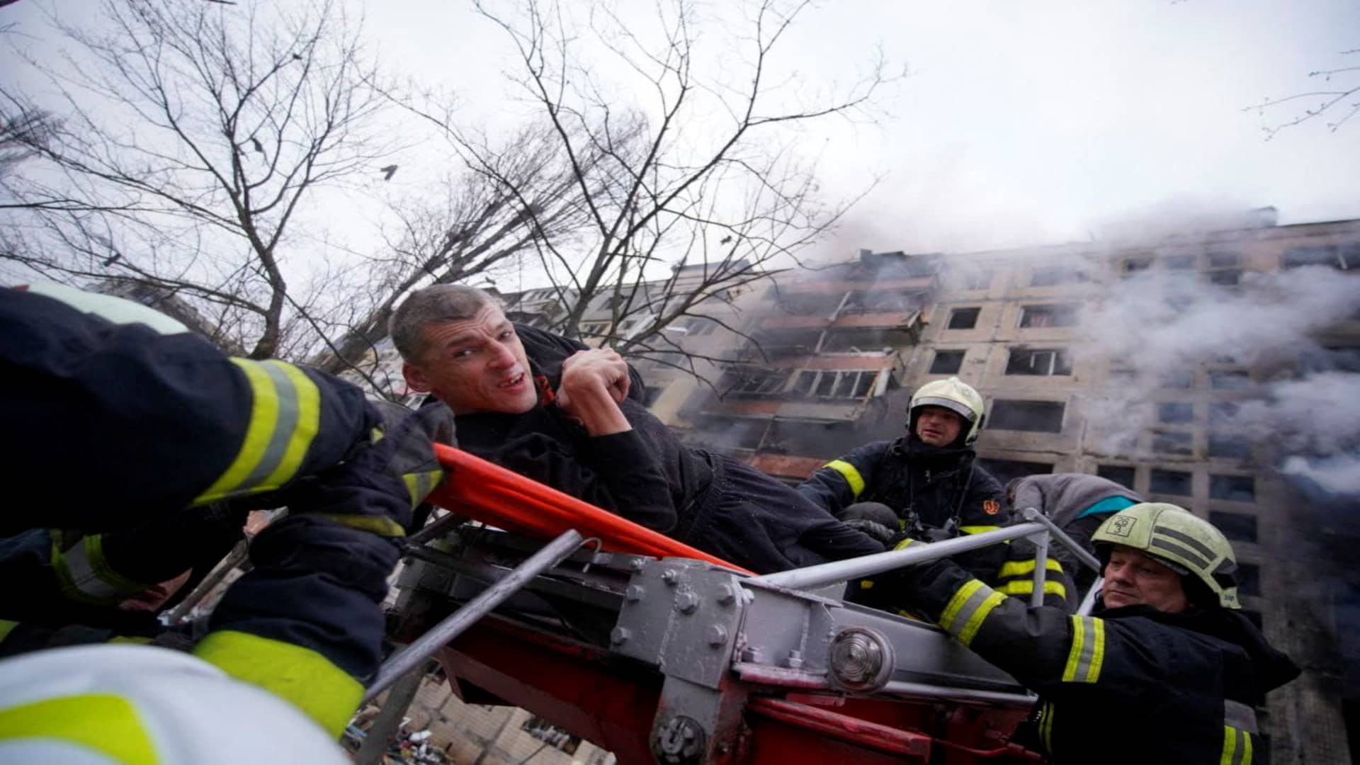 Firefighters use a ladder to evacuate a man from a residential building that was struck, as Russia's attack on Ukraine continues, in Kyiv, Ukraine, in this handout picture released March 14, 2022. 