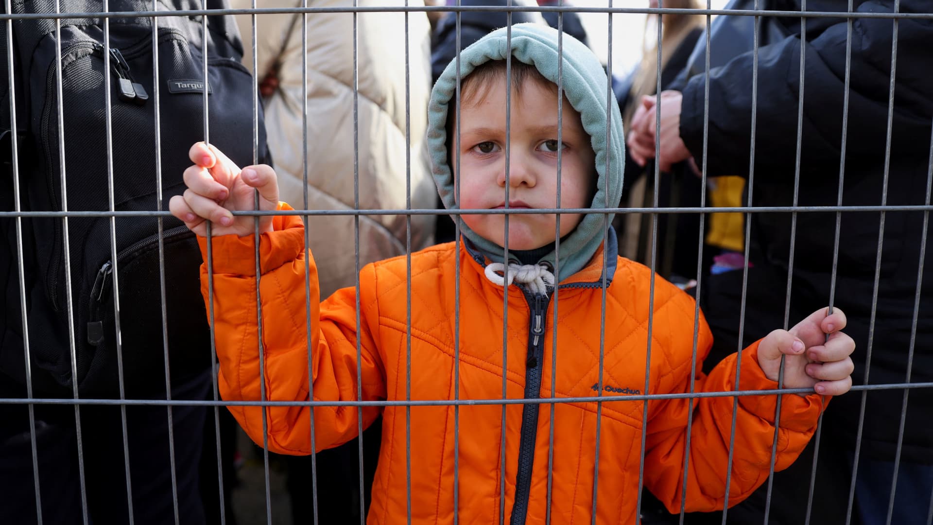 A child stands next to a fence, as people wait outside an immigration office after fleeing from Ukraine to Belgium, following Russia's invasion of Ukraine, in Brussels, Belgium, March 14, 2022.