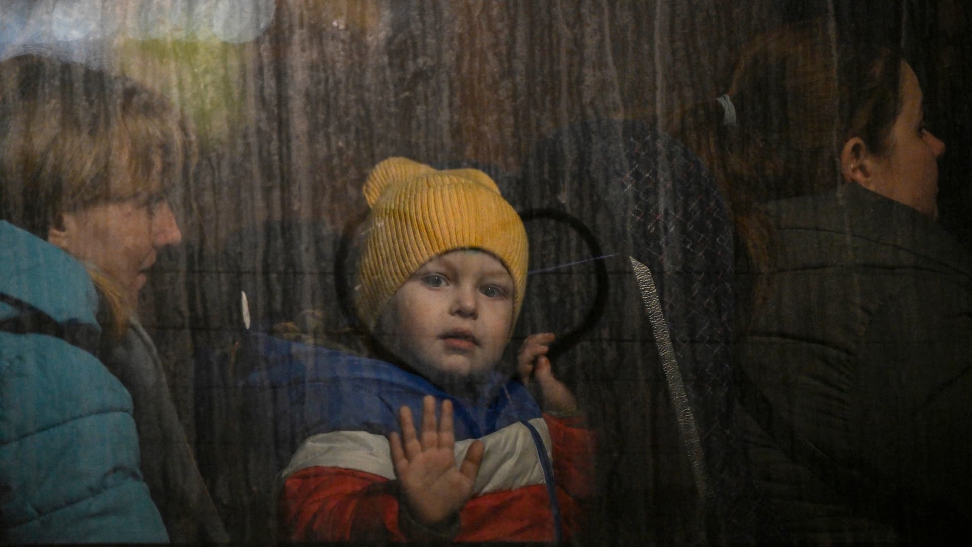 A child greets from the window of a bus after crossing the Ukrainian border with Poland at the Medyka border crossing, southeastern Poland, on March 14, 2022.