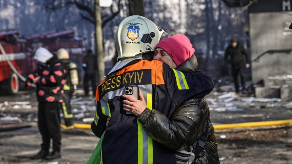 TOPSHOT - A fireman embraces a woman outside a damaged apartment building in Kyiv on March 15, 2022, after strikes on residential areas killed at least two people, Ukraine emergency services said as Russian troops intensified their attacks on the Ukrainia