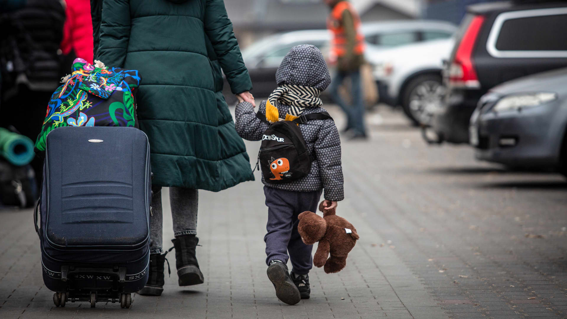 A displaced Ukrainian and child make their way to board a bus for onward travel at a temporary refugee center, setup at a disused Tesco building, in Przemysl, Poland, on Wednesday, March 16, 2022.