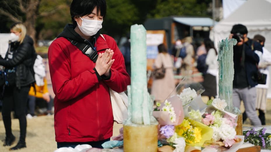A woman prays in front of a temporary altar at the Hibiya Park in Tokyo, Japan, on March 11, 2022 to commemorate the victims of a magnitude-9.0 earthquake and ensuing tsunami that hit Japan's northeast on March 11, 2011.