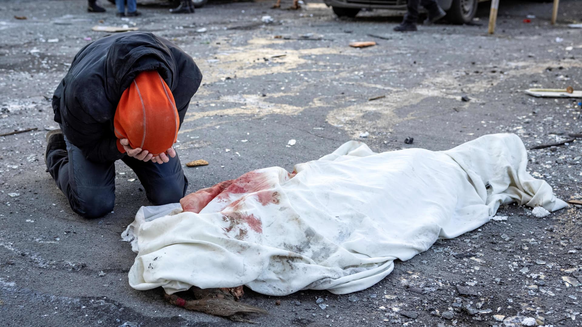 EDITORS NOTE: Graphic content / A person mourns next to a wrapped body near a residential building which was hit by the debris from a downed rocket in Kyiv on March 17, 2022.