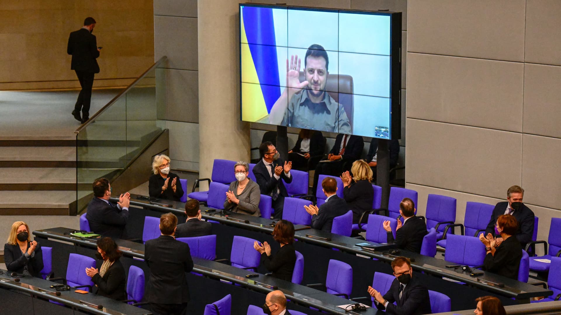 Members of the German government, among them German Chancellor Olaf Scholz applaud as Ukrainian President Volodymyr Zelensky appears on a screen to address via videolink the German lower house of parliament Bundestag, on March 17, 2022 in Berlin.
