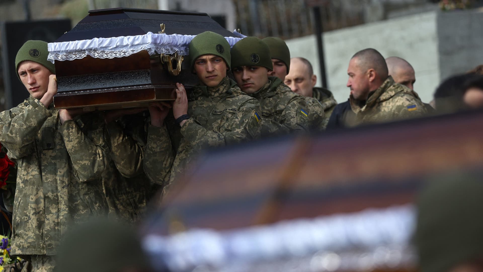 Servicemen hold coffins as relatives and friends mourn the death of four fallen Ukrainian servicemen, Oleg Vashchyshyn, Kyrylo Vyshyvanyi, Rostyslav Romanchuk and Serhiy Melnyk, who were killed in a rocket attack against a military base in Yavoriv during the ongoing Russian invasion, during a memorial and funeral service in Lviv, Ukraine, March 15, 2022. REUTERS/Kai Pfaffenbach