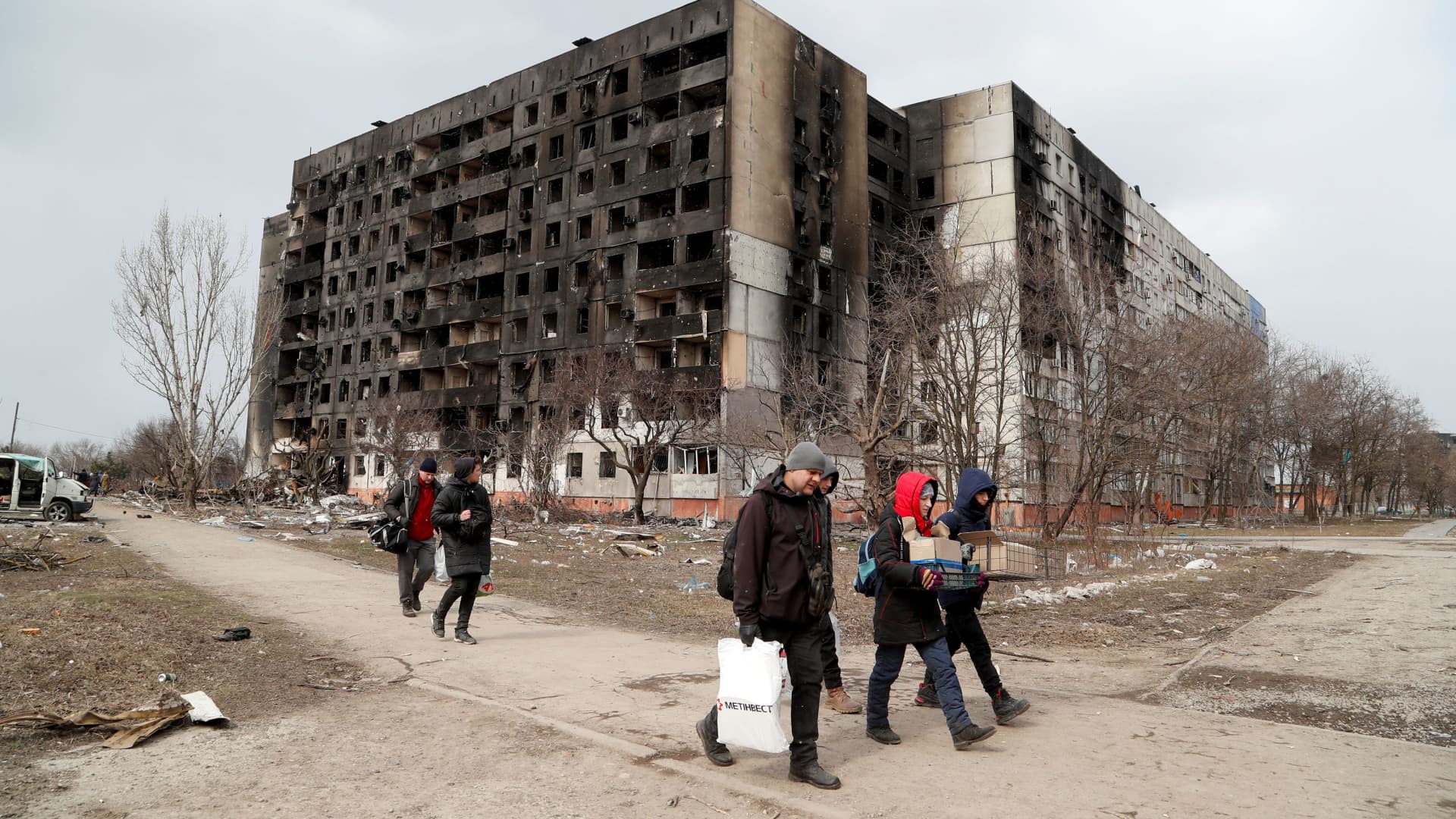 People walk along a street near a block of flats, which was destroyed during Ukraine-Russia conflict in the besieged port city of Mariupol, Ukraine March 17, 2022.