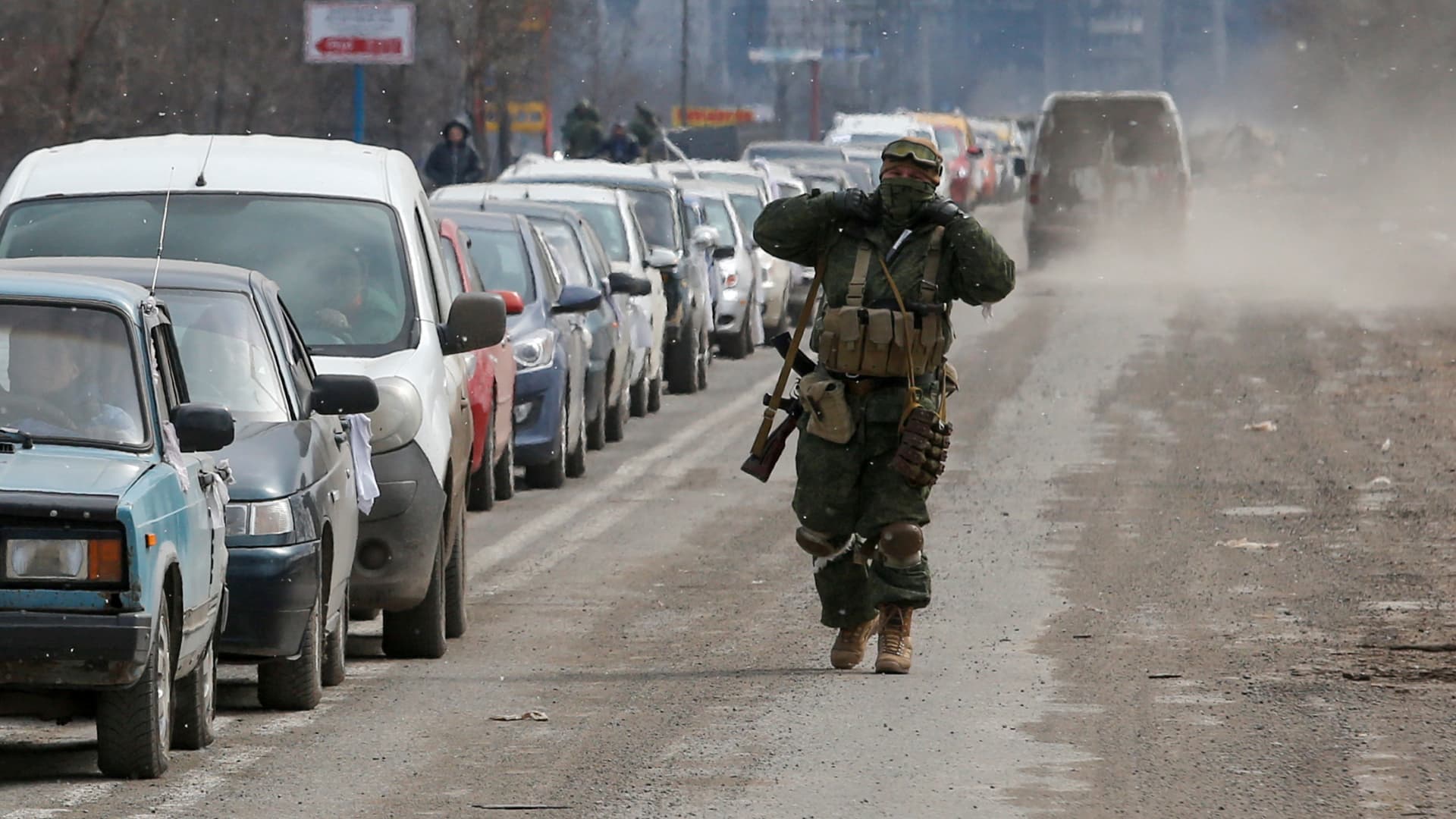 A service member of pro-Russian troops walks near a line of cars with evacuees, who leave the besieged southern port city of Mariupol, Ukraine March 17, 2022.