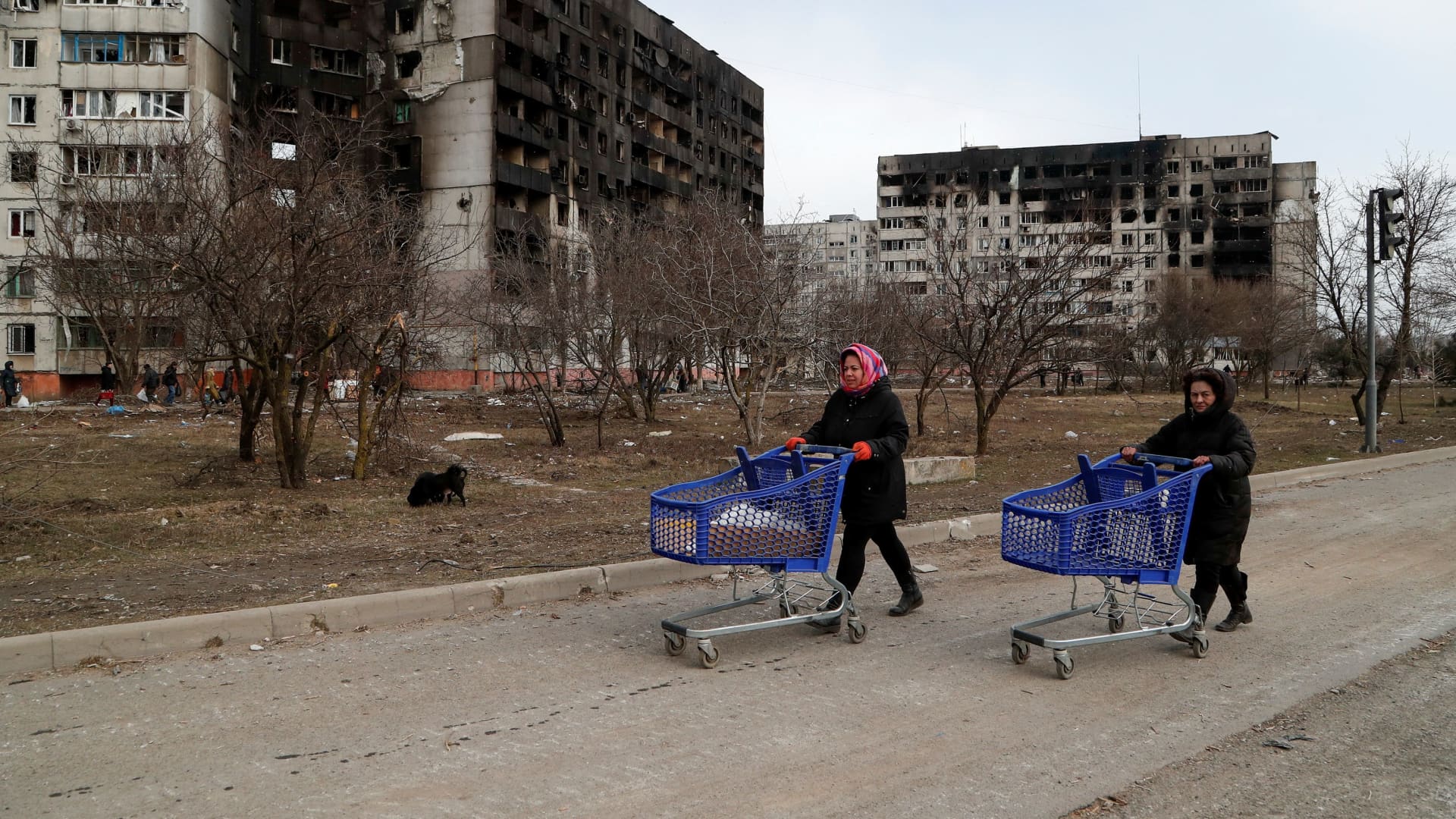 People push carts near blocks of flats, which were damaged during Ukraine-Russia conflict in the besieged southern port city of Mariupol, Ukraine March 17, 2022.
