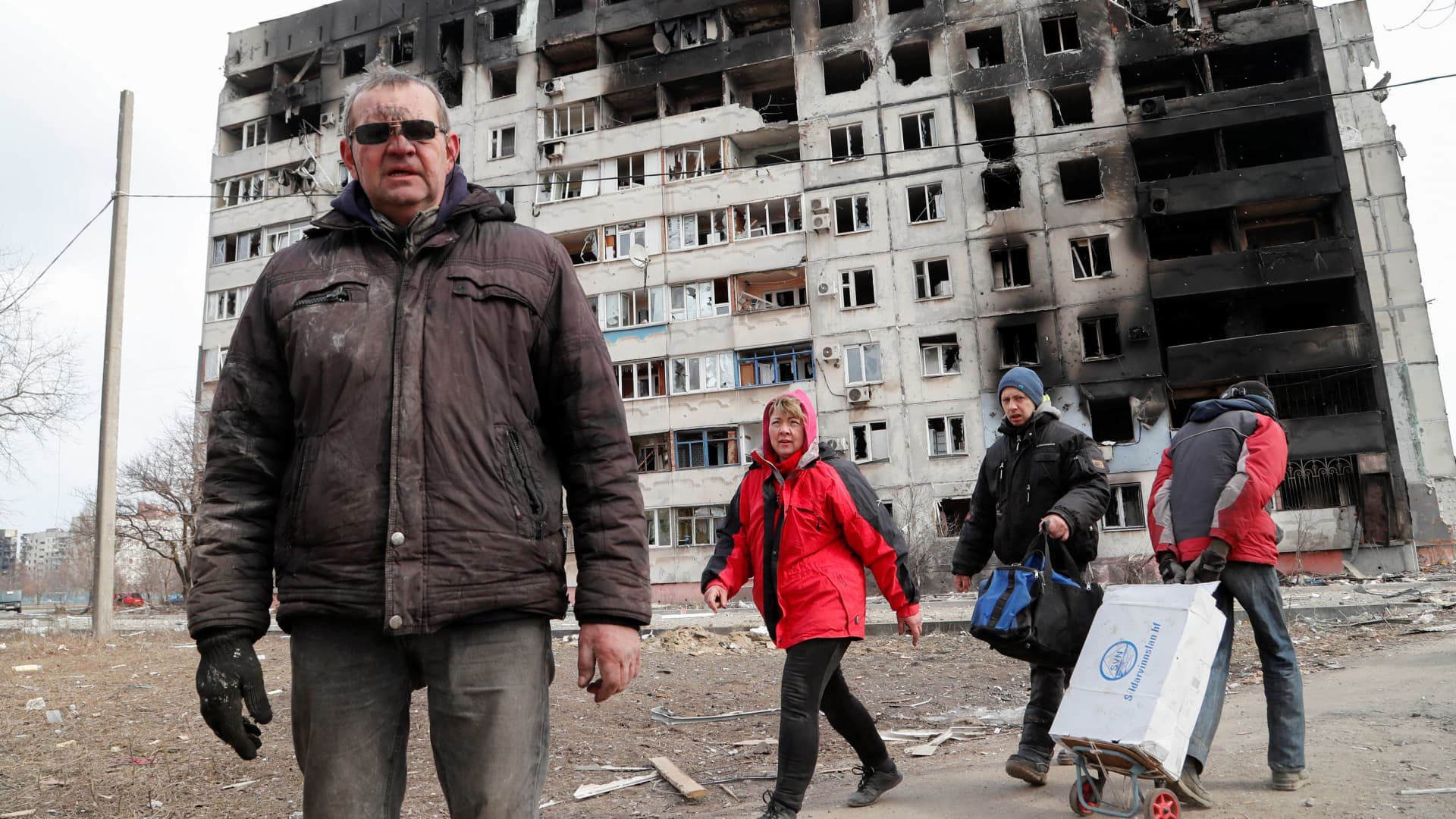 People walk near a block of flats, which was destroyed during Ukraine-Russia conflict in the besieged southern port city of Mariupol, Ukraine March 17, 2022.