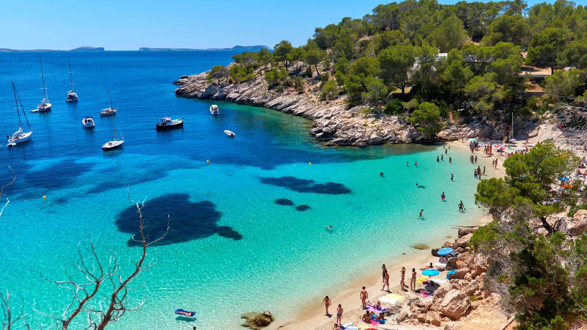 Beachgoers and boaters at Cala Salada, Ibiza.