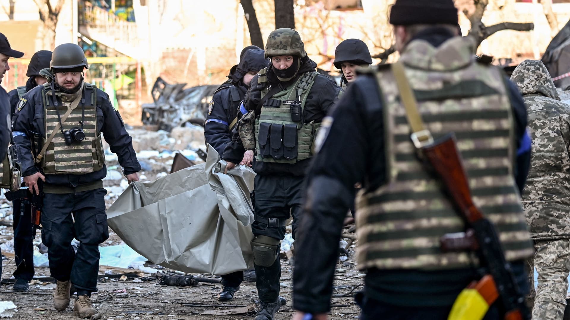 Ukrainian policemen carry a body away from a five-storey residential building that partially collapsed after a shelling in Kyiv on March 18, 2022, as Russian troops try to encircle the Ukrainian capital as part of their slow-moving offensive.