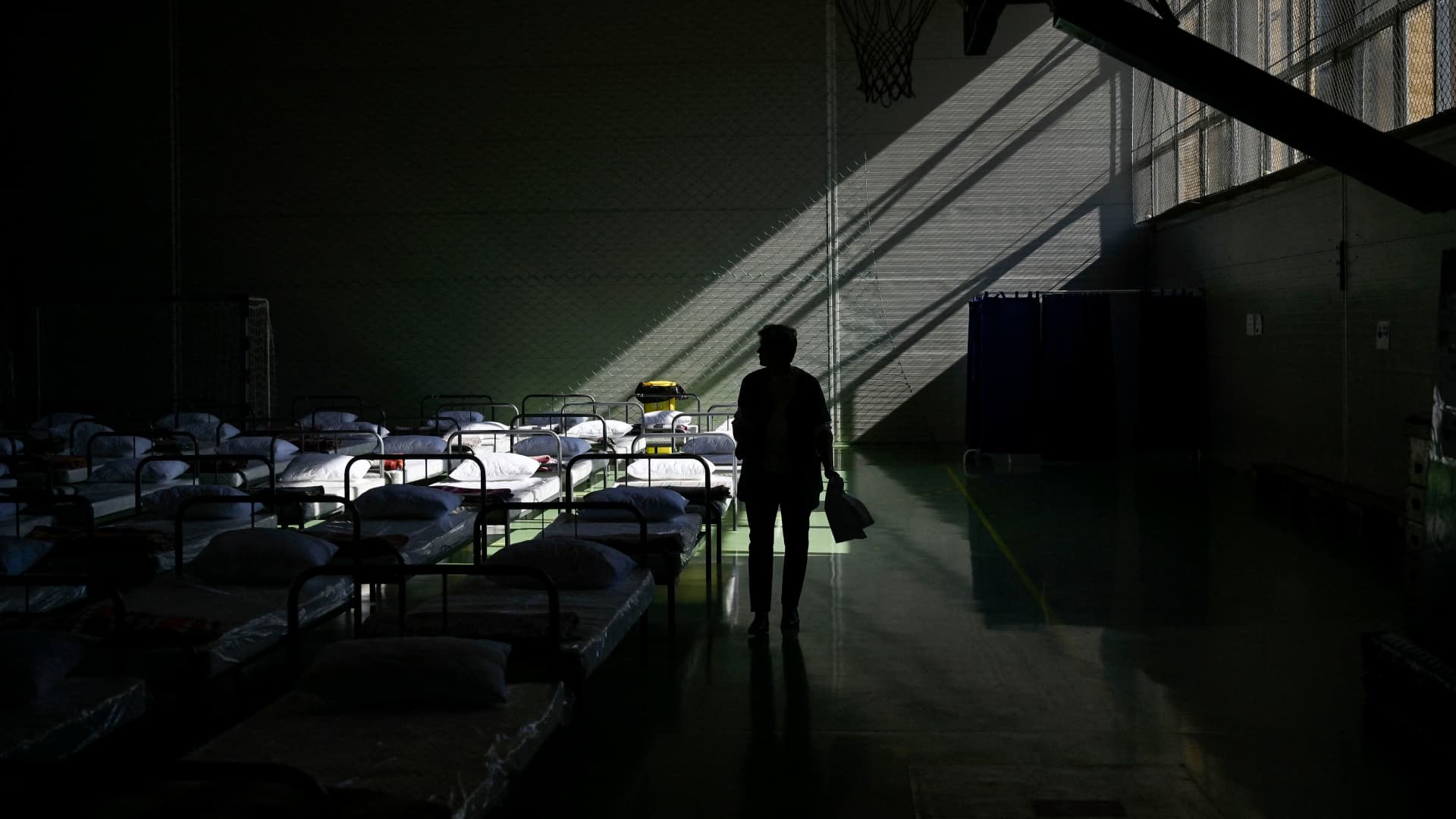 An Ukrainian evacuee walks past beds that have been prepared in a school gym which has been converted into a shelter for Ukrainian refugees in the town of Suceava, Romania on March 18, 2022.
