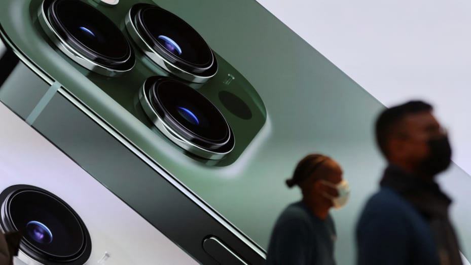 Customers walk past a digital display of the new green color Apple iPhone 13 pro inside the Apple Store on 5th Avenue in Manhattan, in New York, March 18, 2022.