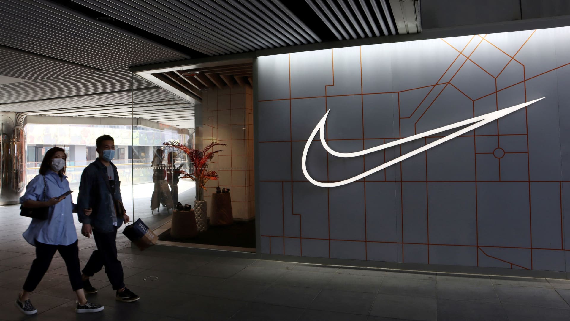 People walk past a store of the sporting goods retailer Nike Inc. at a shopping complex in Beijing, China March 25, 2021.