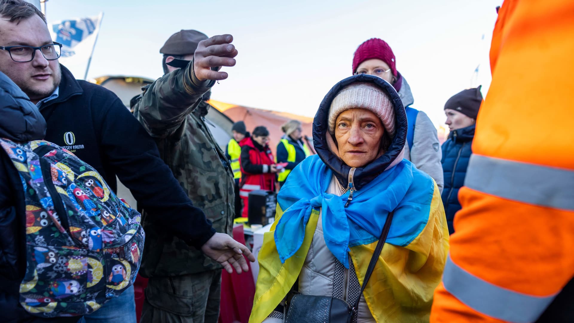 People, including an elderly woman wearing a Unkraine flag, line up to get into the buses for further transportation at the Medyka Polish-Ukrainian border crossing on March 18, 2022.