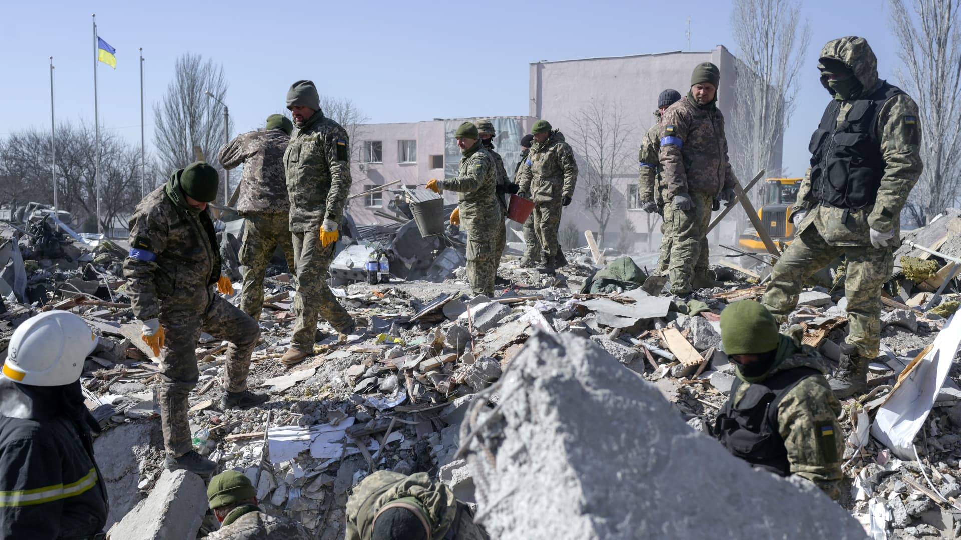 Ukrainian soldiers search for bodies in the debris at the military school hit by Russian rockets the day before, in Mykolaiv, southern Ukraine, on March 19, 2022.