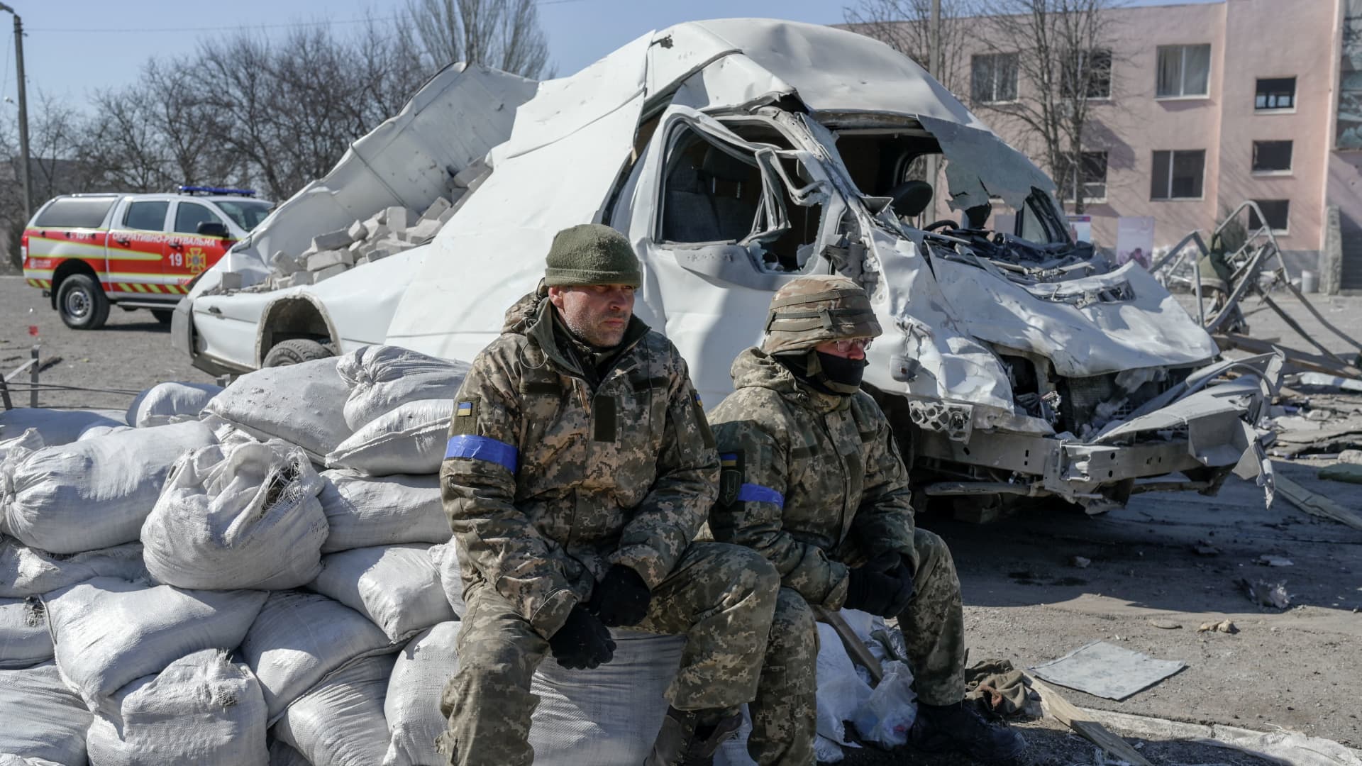 Ukrainian soldiers sit next to the military school hit by Russian rockets the day before, in Mykolaiv, southern Ukraine, on March 19, 2022.