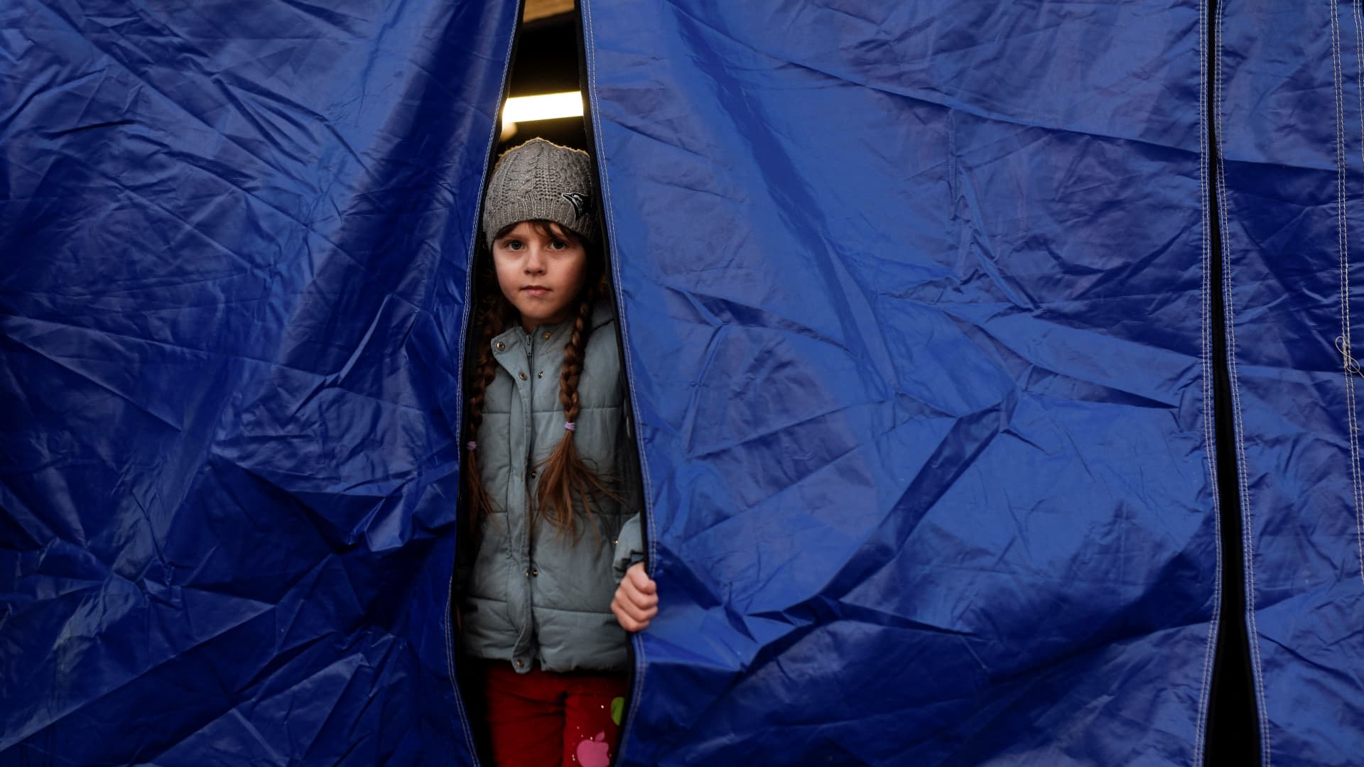 An Ukrainian child looks out of a tent while waiting for relocation after crossing the Ukrainian-Romanian border in Siret, northern Romania, on March 19, 2022.
