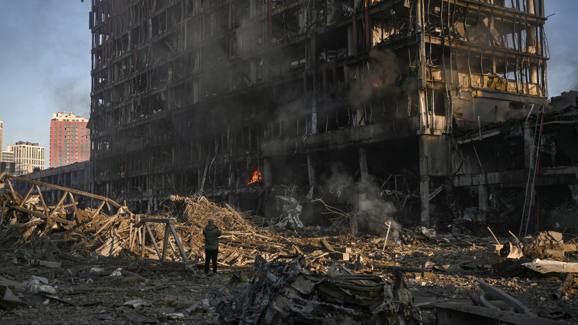 A man stand looking at the burning and destroyed Retroville shopping mall after a Russian attack on the northwest of the capital Kyiv on March 21, 2022.