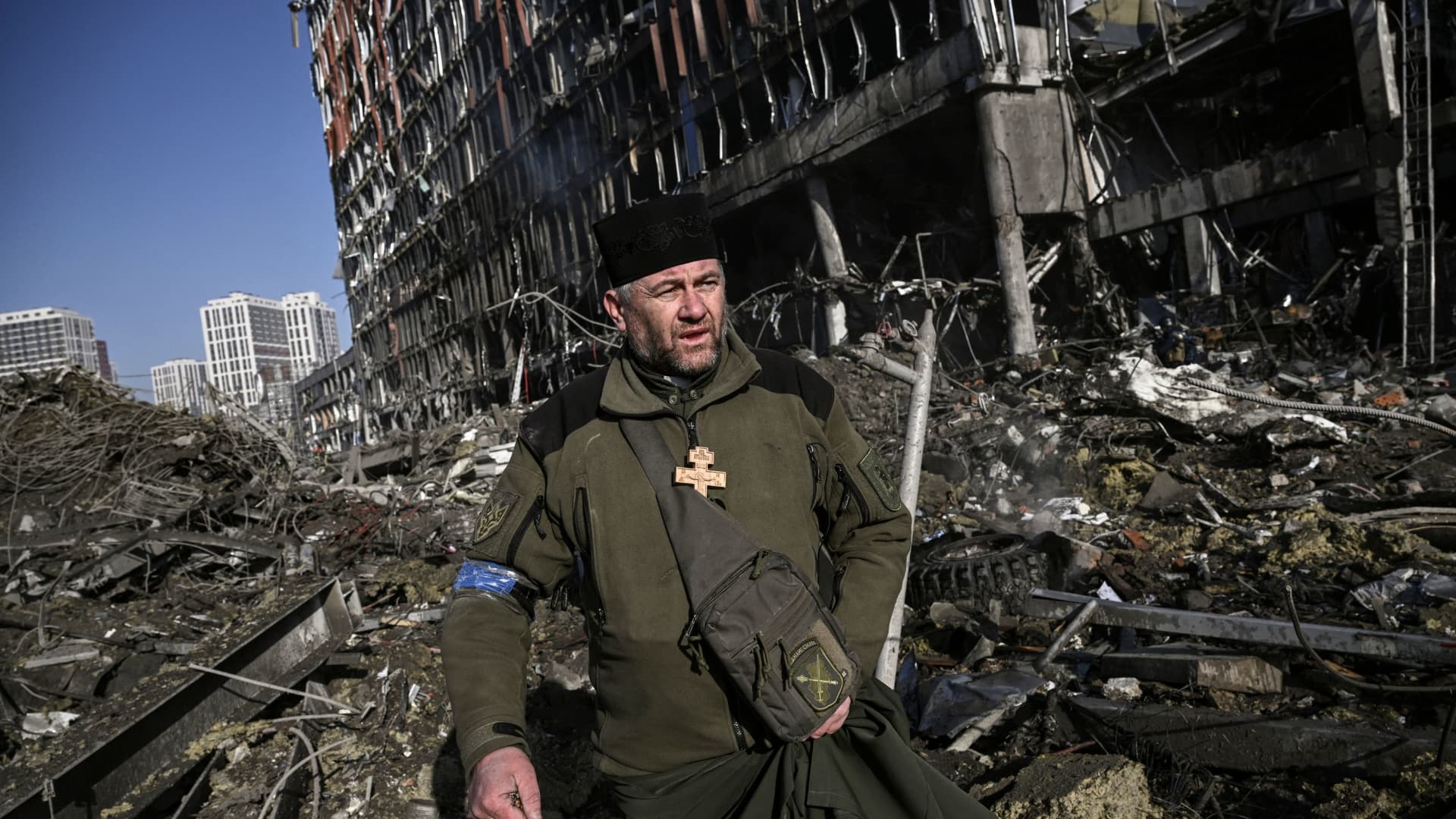 Ukraine army Chaplain Mikola Madenski walks through debris outside the destroyed Retroville shopping mall in a residential district, after a Russian attack on the Ukranian capital Kyiv on March 21, 2022.
