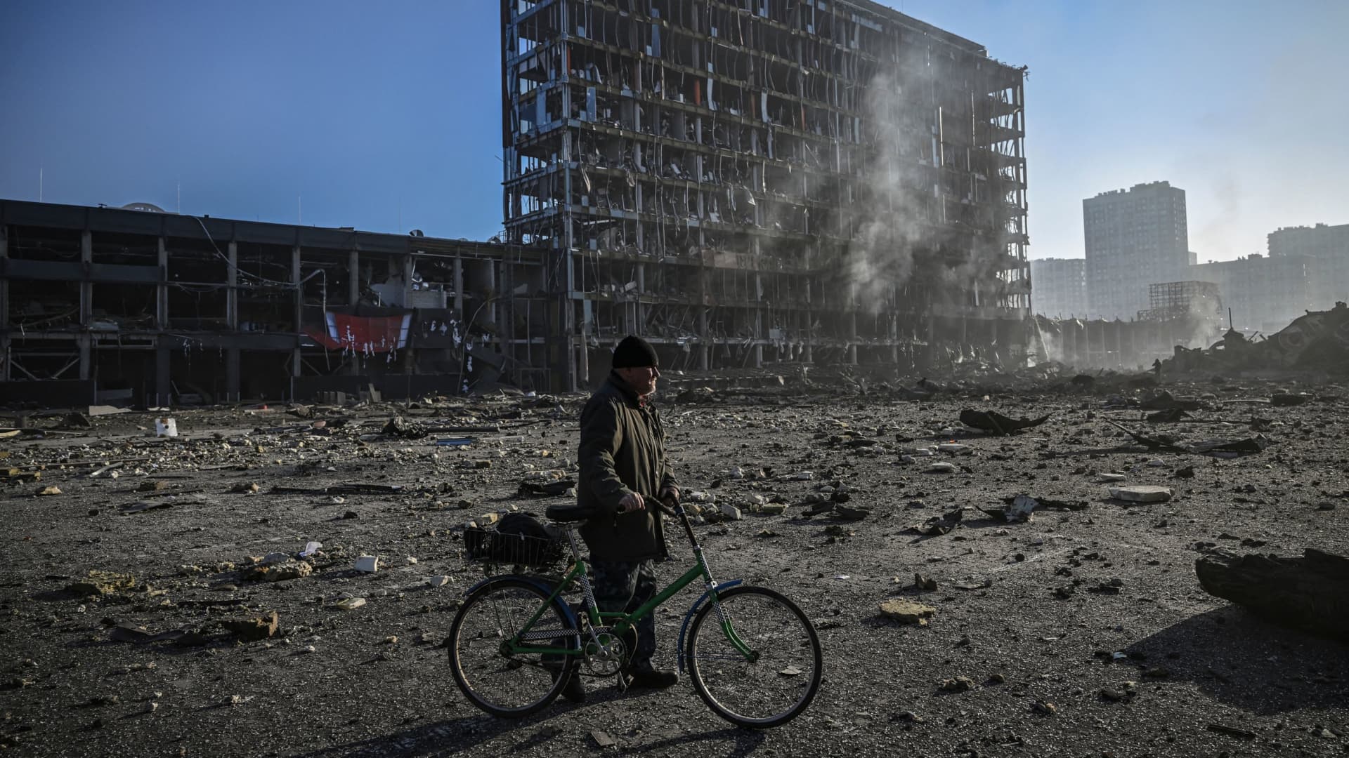A man with his bicycle walks between debris outside the destroyed Retroville shopping mall in a residential district, after a Russian attack on the Ukranian capital Kyiv on March 21, 2022.